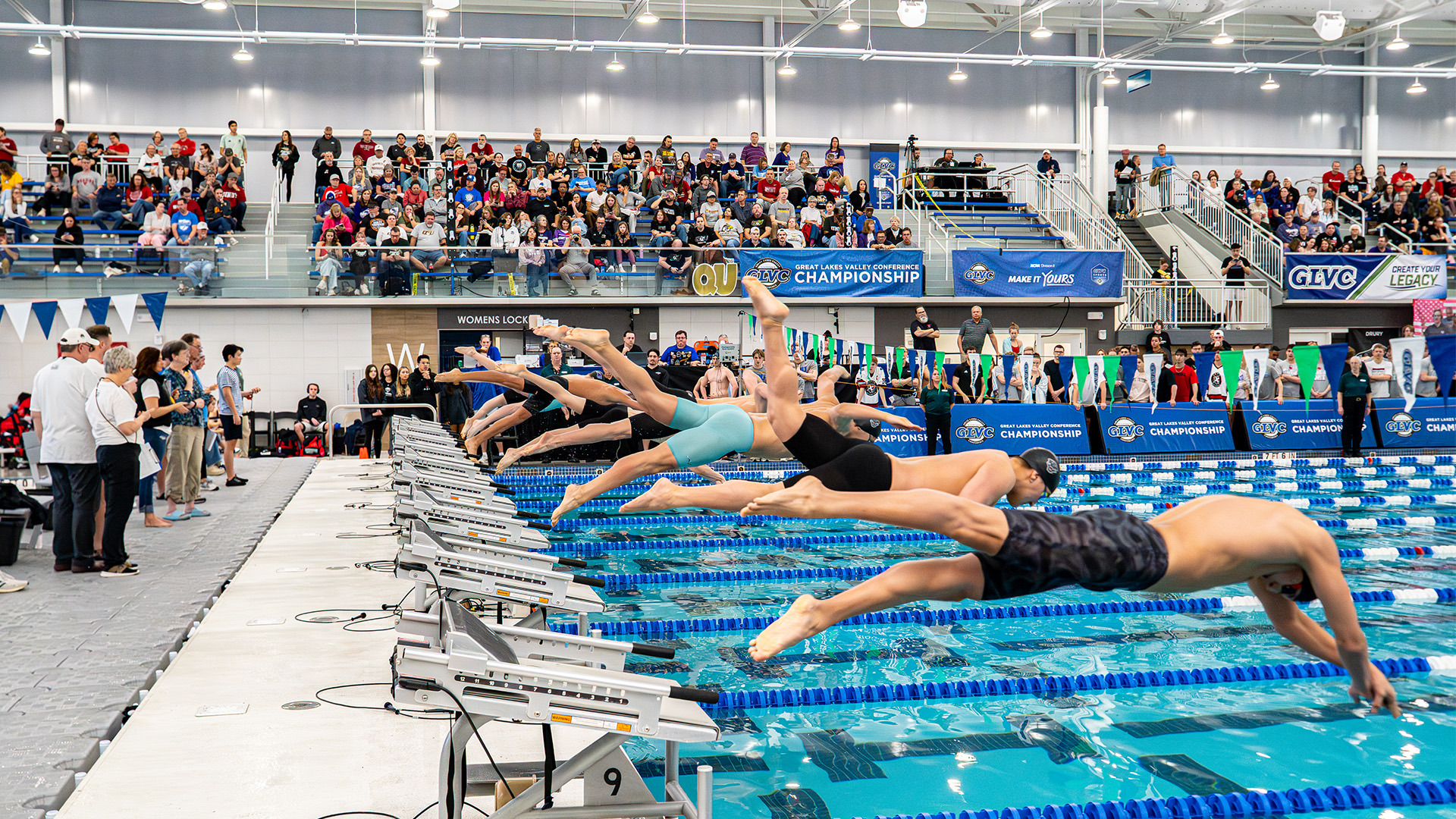 Swimmers jump off the starting block at the 2026 GLVC Swimming & Diving Championships.