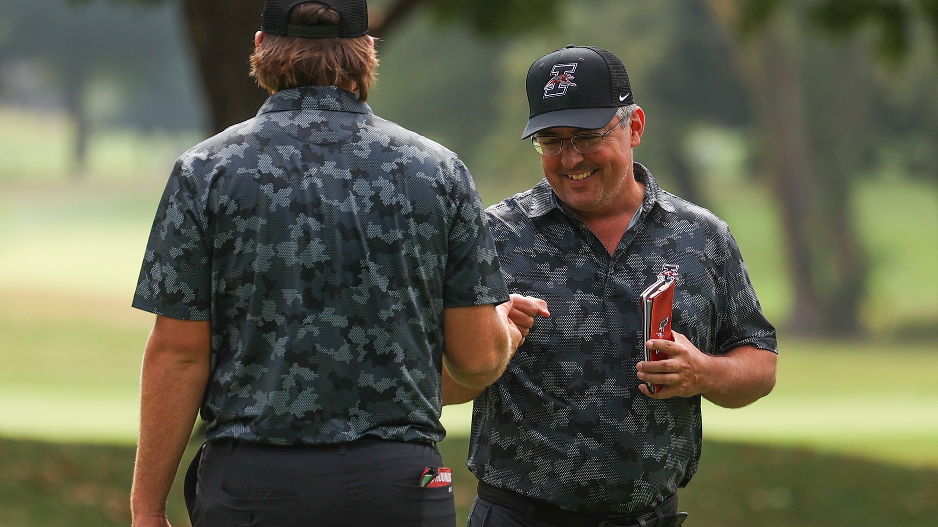 UIndy golf head coach Andy Serketich fist bumps one of his student-athletes.