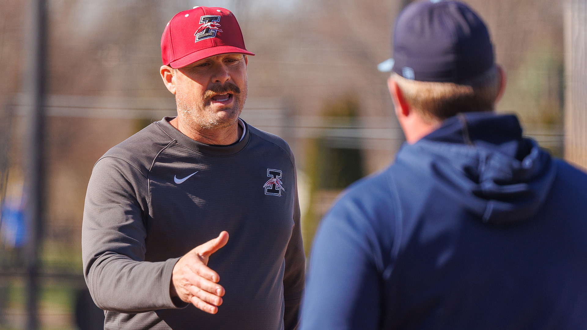 UIndy baseball head coach Al Ready reaching out to shake the hand of the opposing coach.
