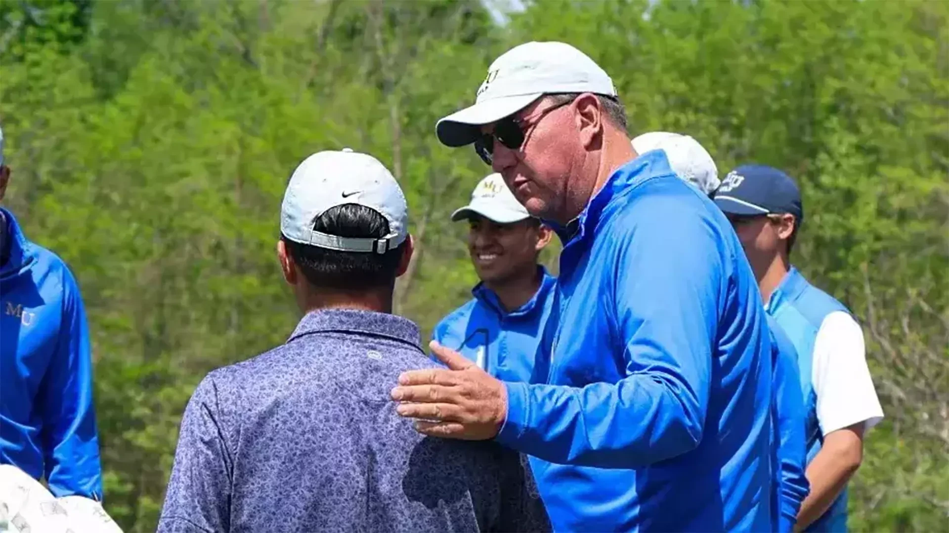 Steve Simmons patting a student-athlete on the back during his time as the Marian men's golf head coach.