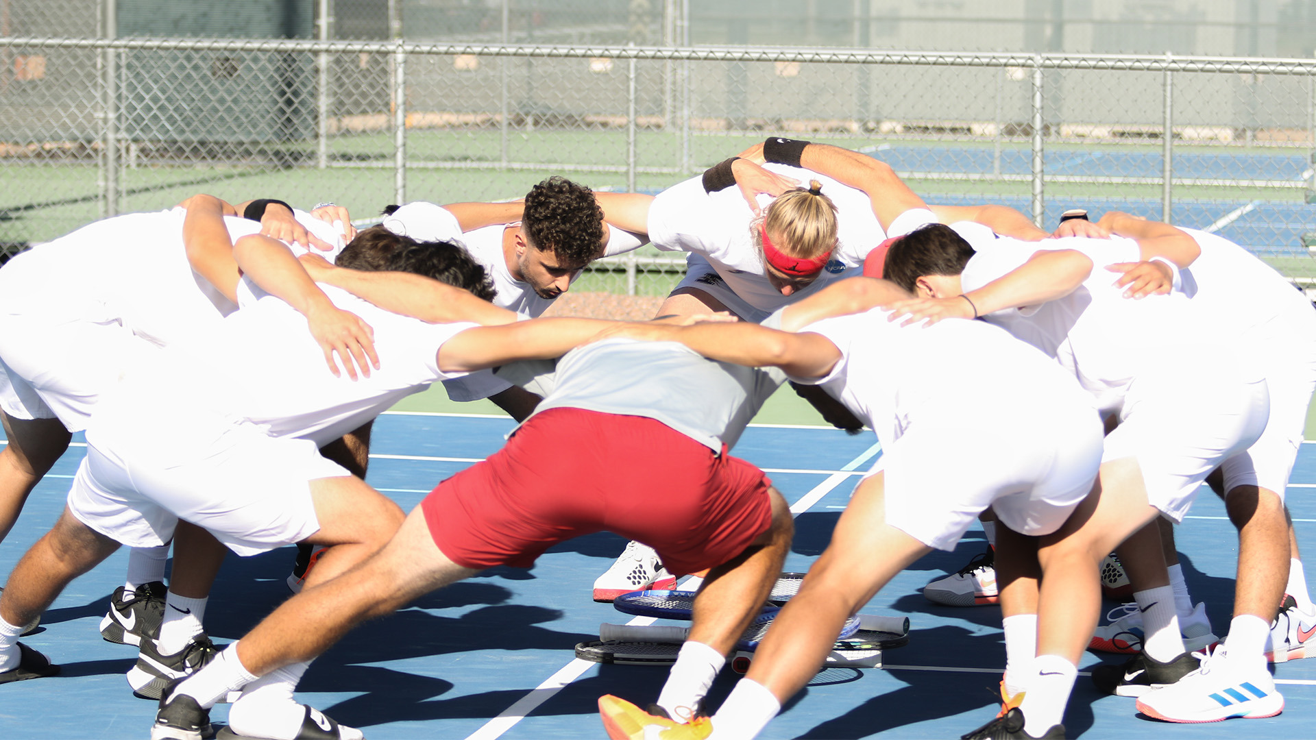 Members of the UIndy men's tennis team huddling up.