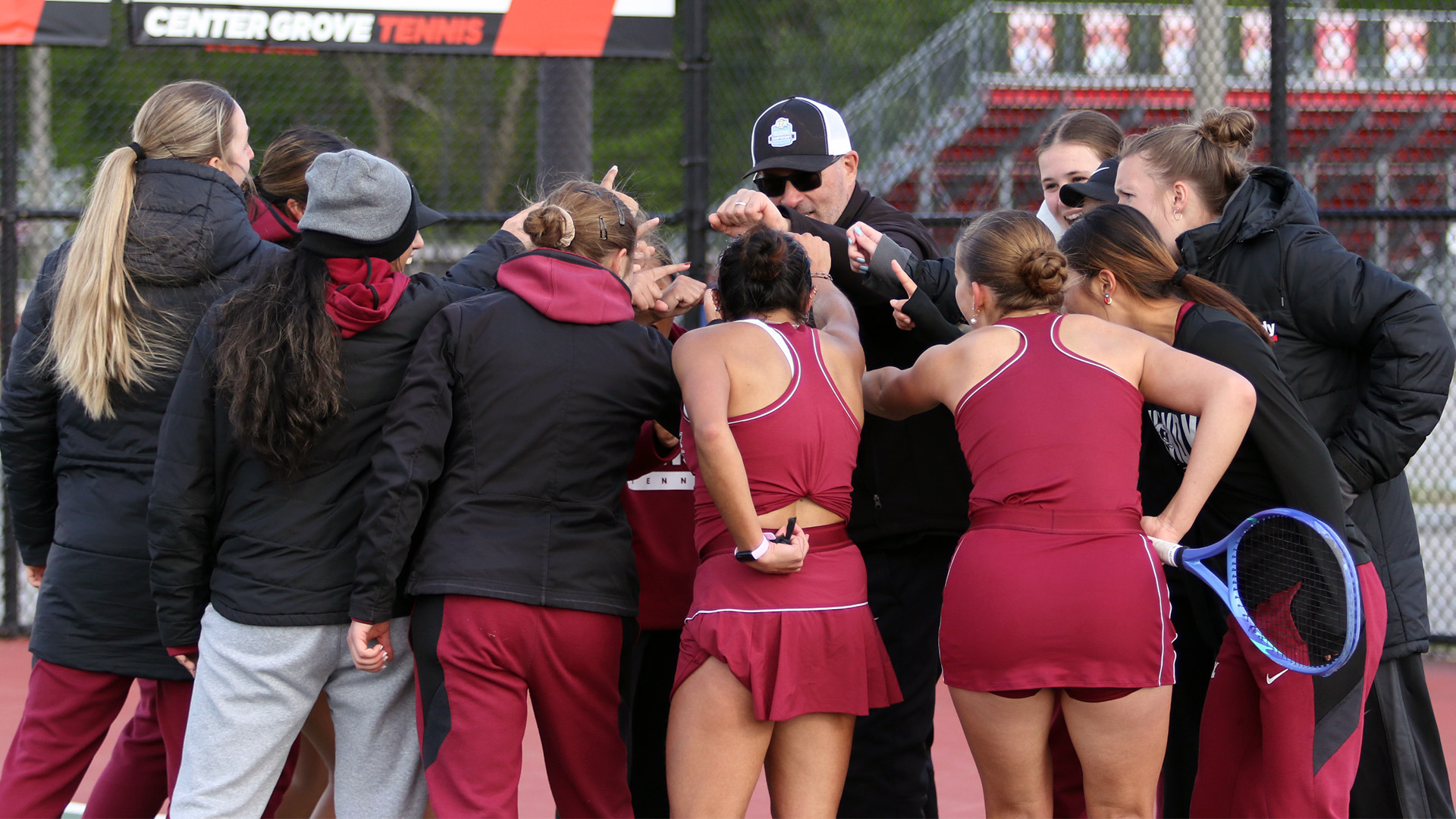 Members of the UIndy women's tennis team huddling up.