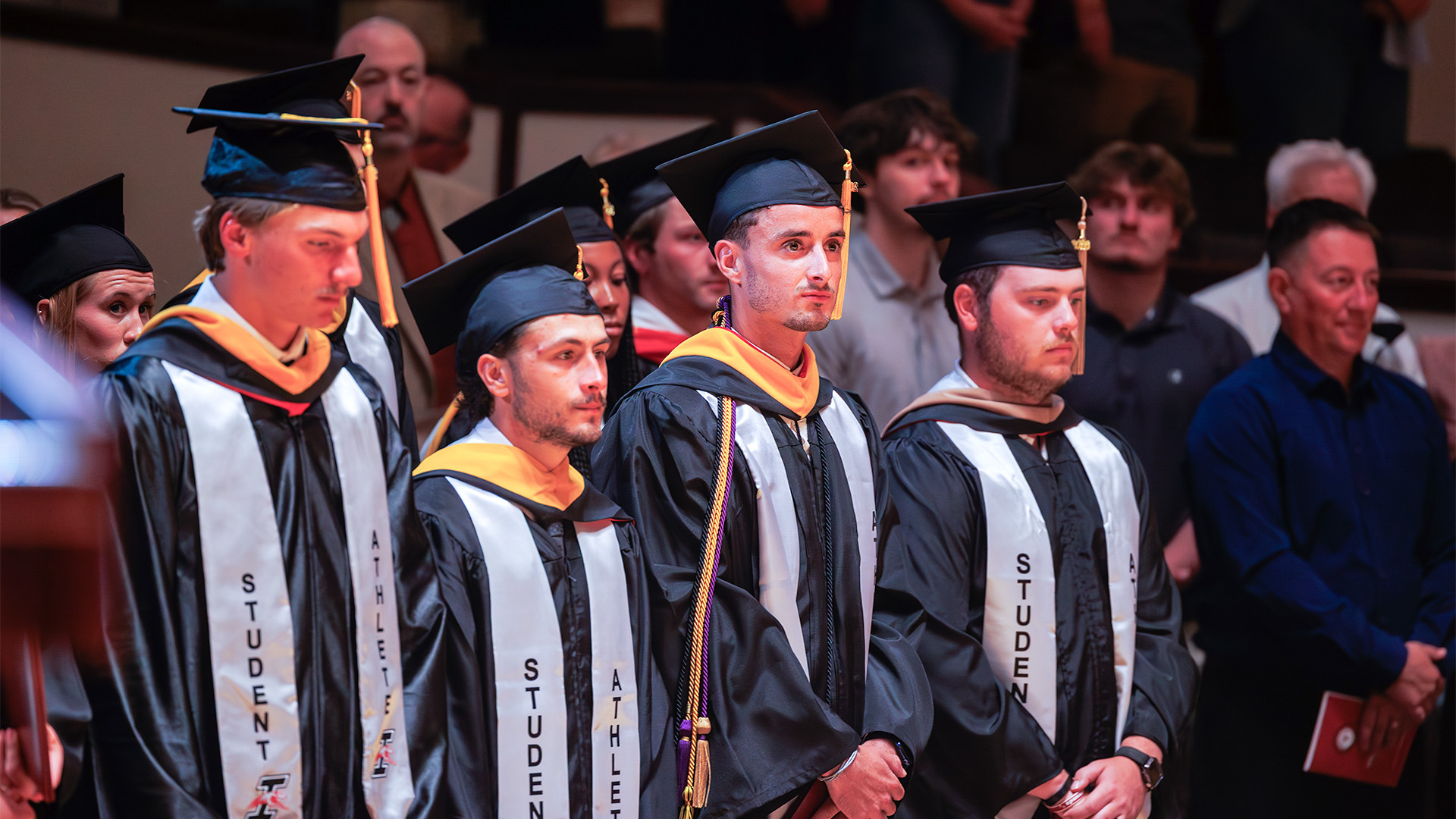 UIndy student-atheltes wearing their cap and gown at graduation.