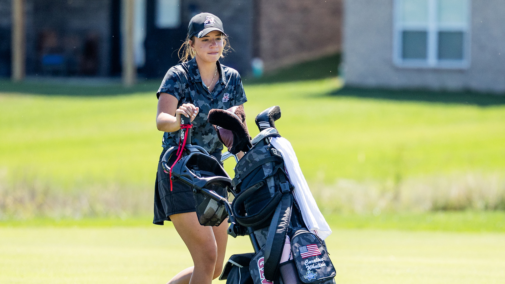UIndy golfer Carilne Whallon pushing her golf bag on the course.