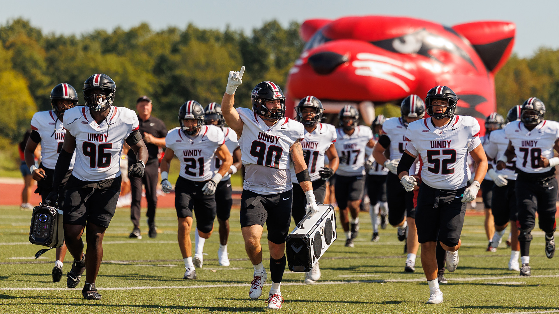 Members of the UIndy football team runnin onto the field for warm-ups.