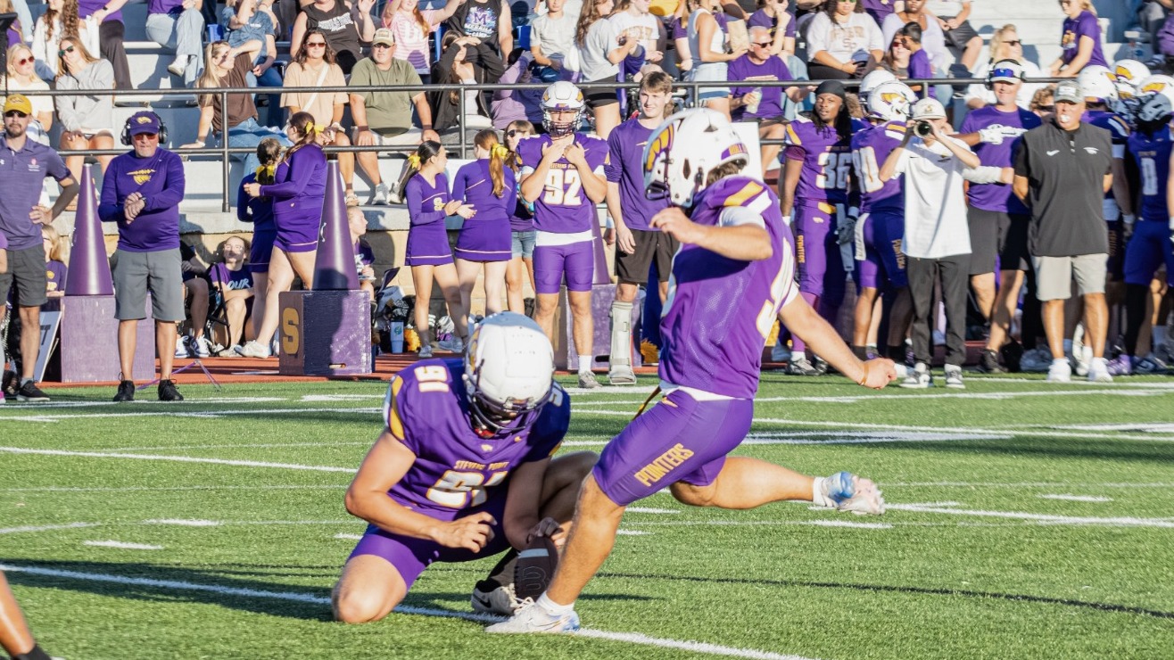 Tyler Sodemann kicks a field hold with Dakota Stroud holding