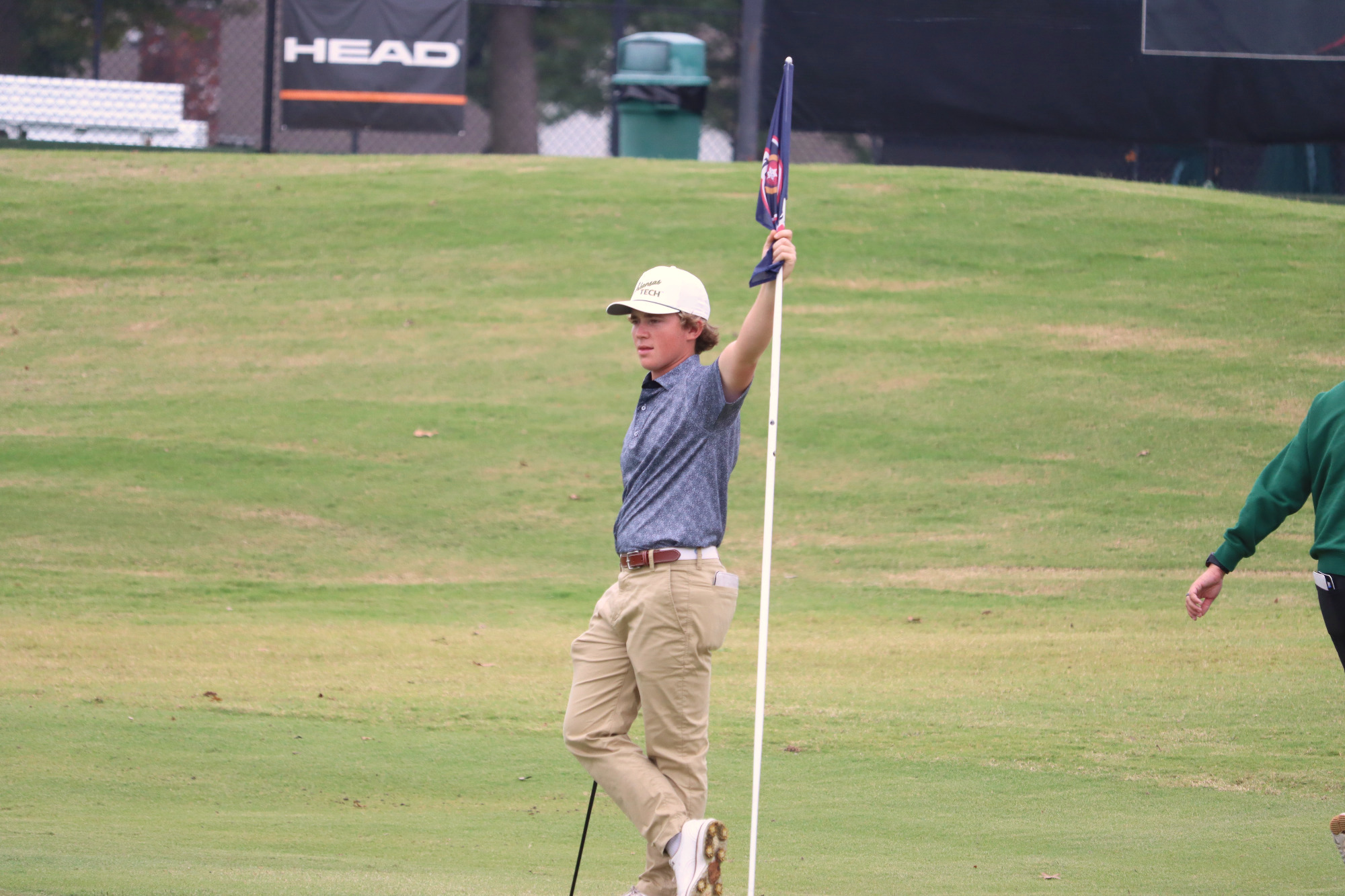 Landon Lawson holding hole flag at Tulsa Cup