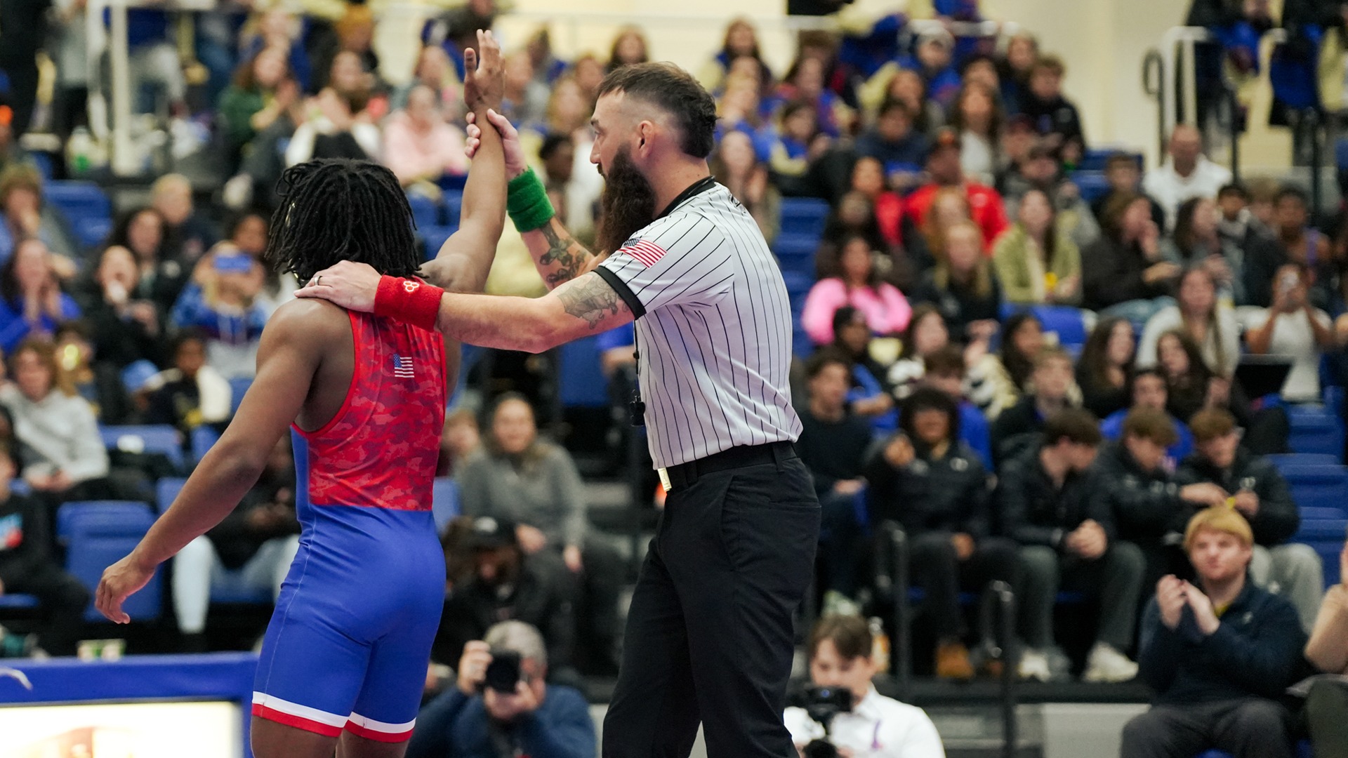 JJ Peace getting his arm raised by an official after winning a wrestling match against Maryland. 
