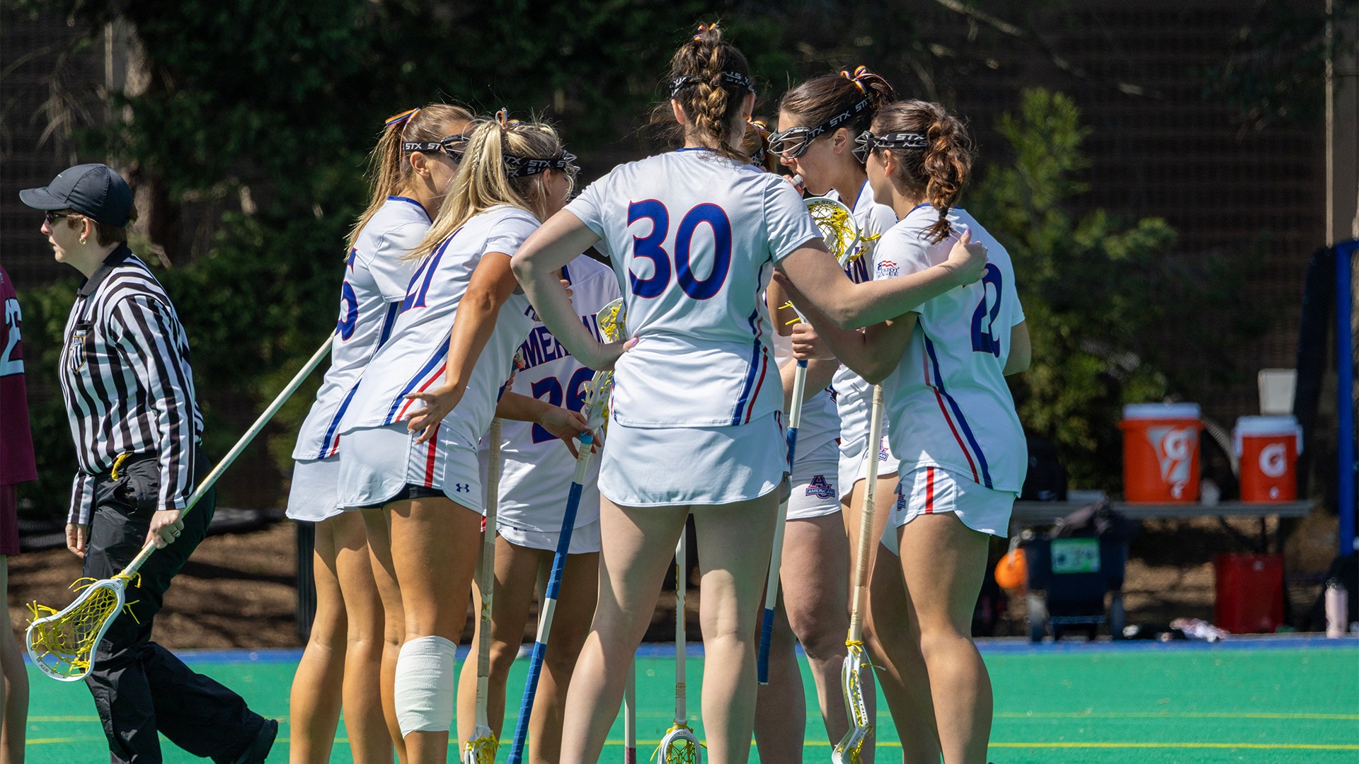The lacrosse team huddling after a goal. 
