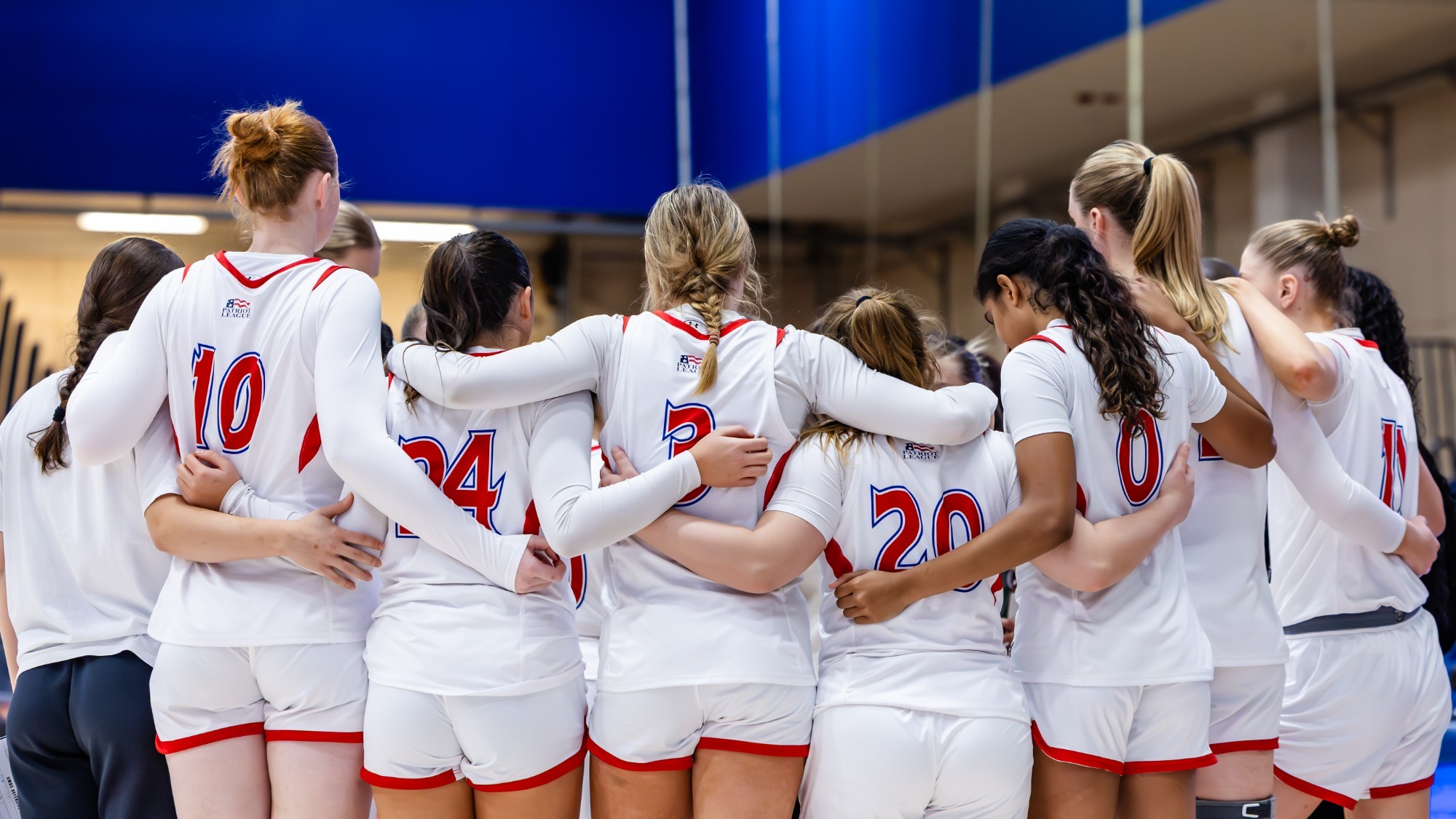 Women's basketball huddles together in Bender Arena during a timeout against UMBC.
