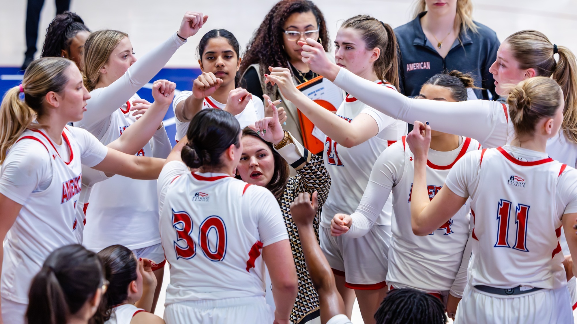 Women's Basketball huddles together on the court against Boston University.