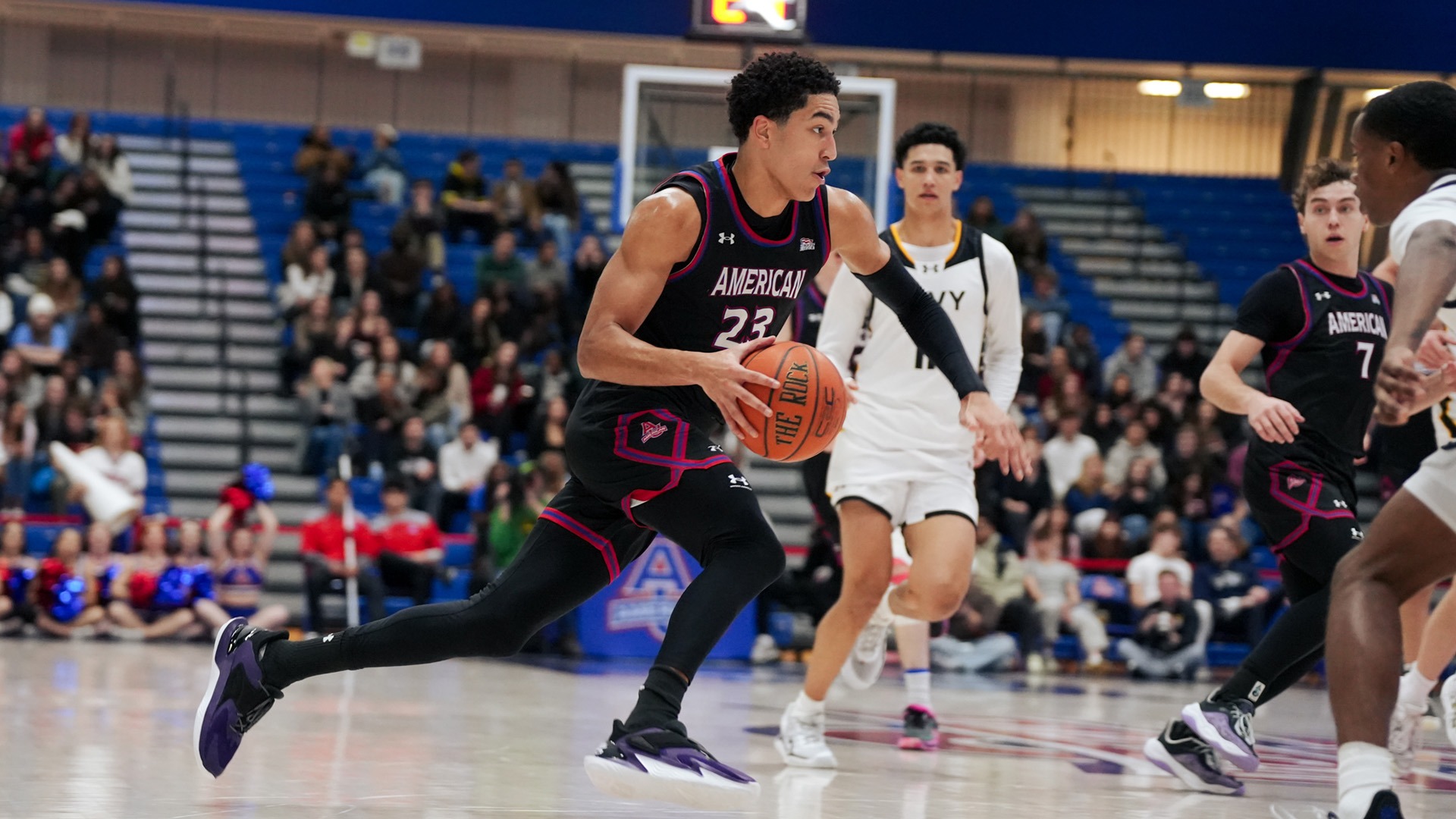 Greg Jones driving the lane with the ball in a men's basketball game against Navy