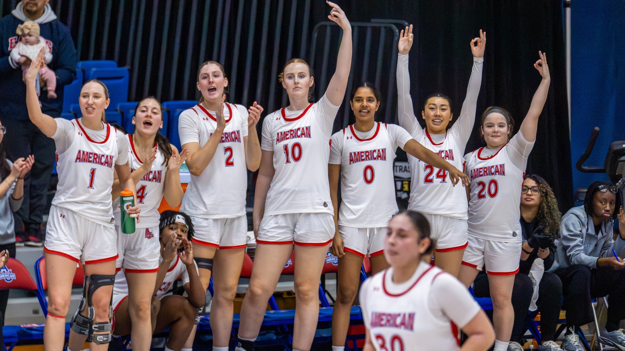 The bench of the women's basketball team celebrating. 