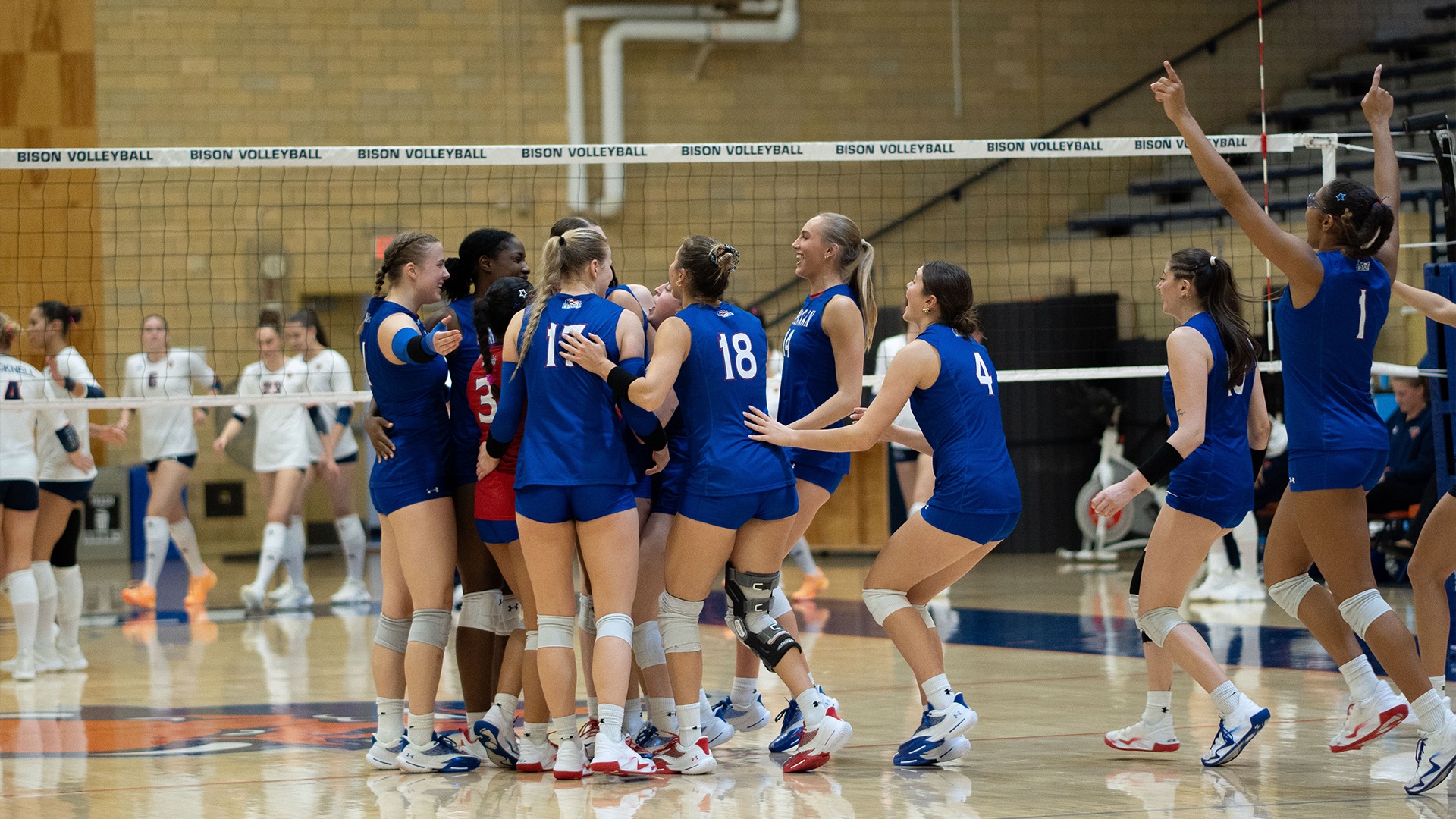 The American University volleyball team celebrating after defeating Bucknell for the program's 1,000th all-time win. 