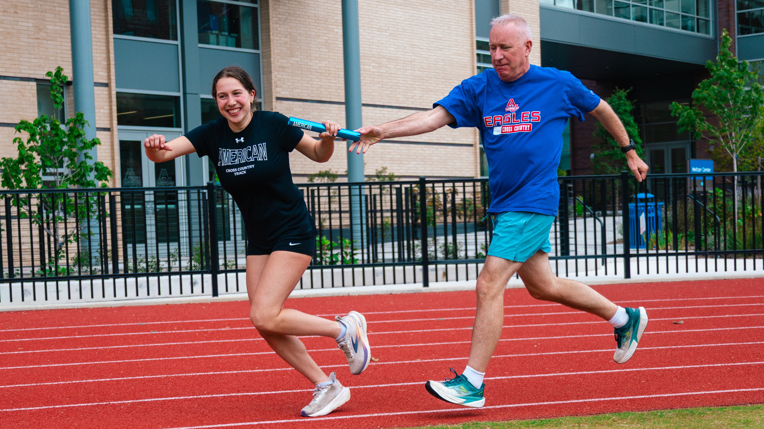 Kevin Boyle passing the baton to AU track and cross country athlete, Zoe Rector.