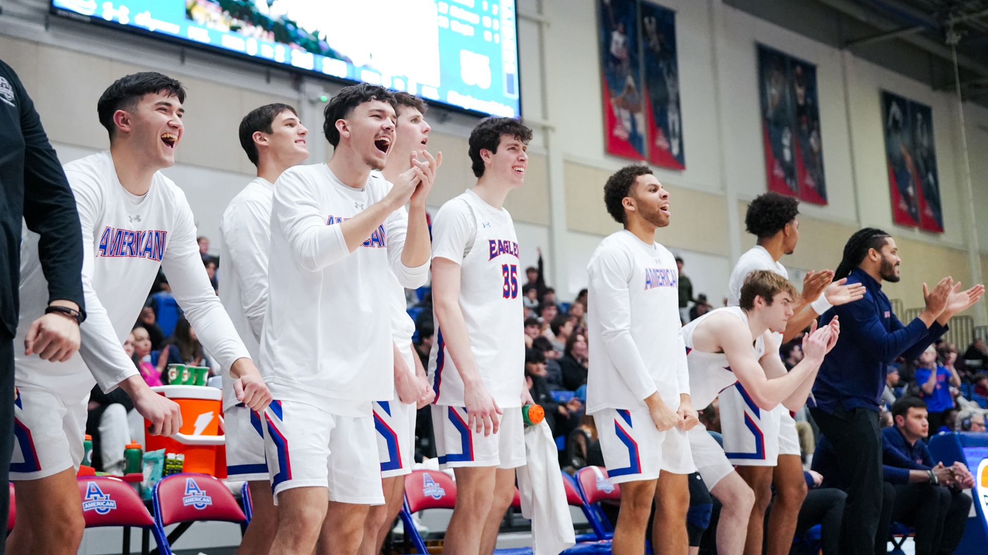 men's basketball players cheering the team on from the bench