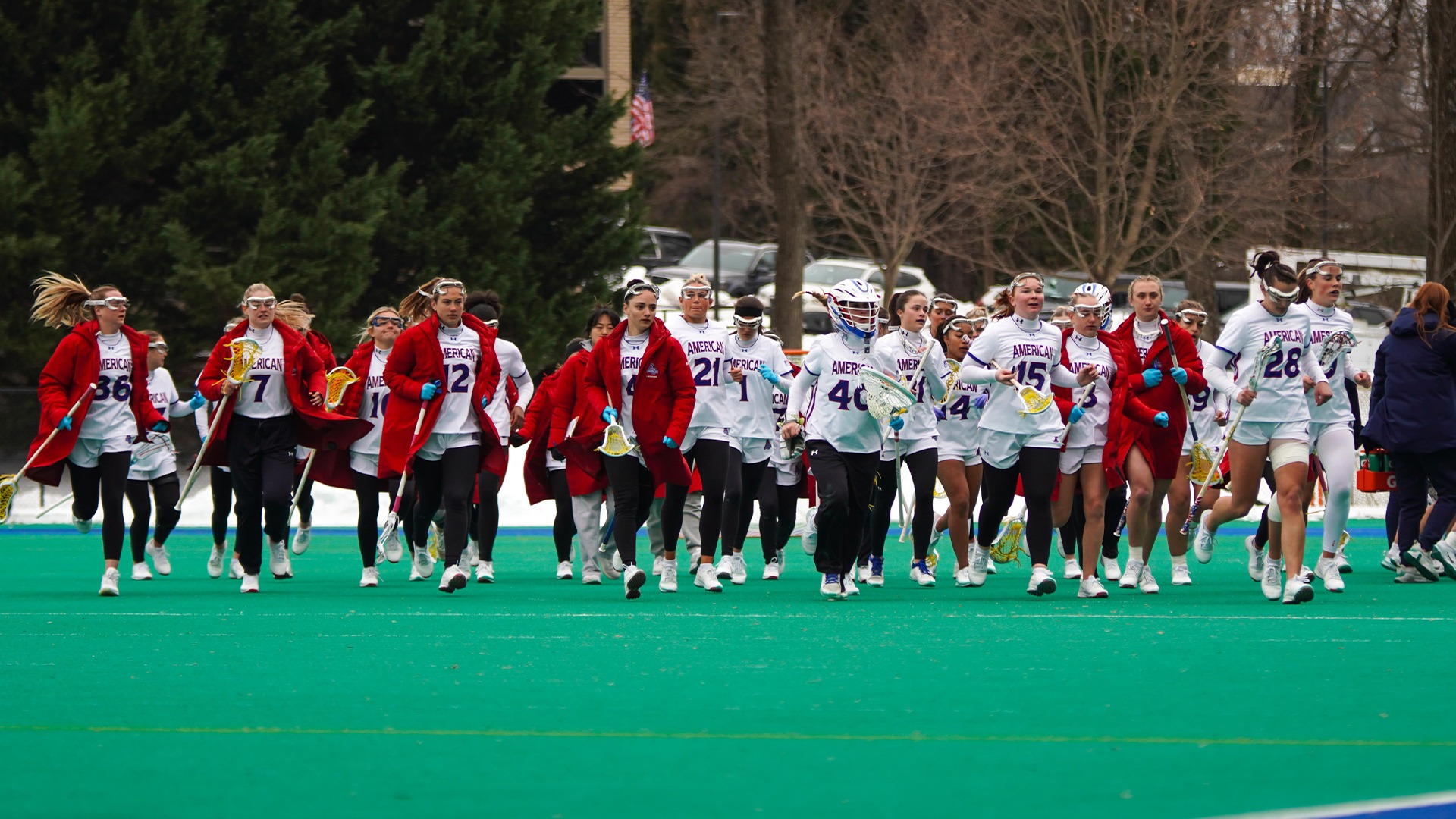 The lacrosse team running on the field before a game.