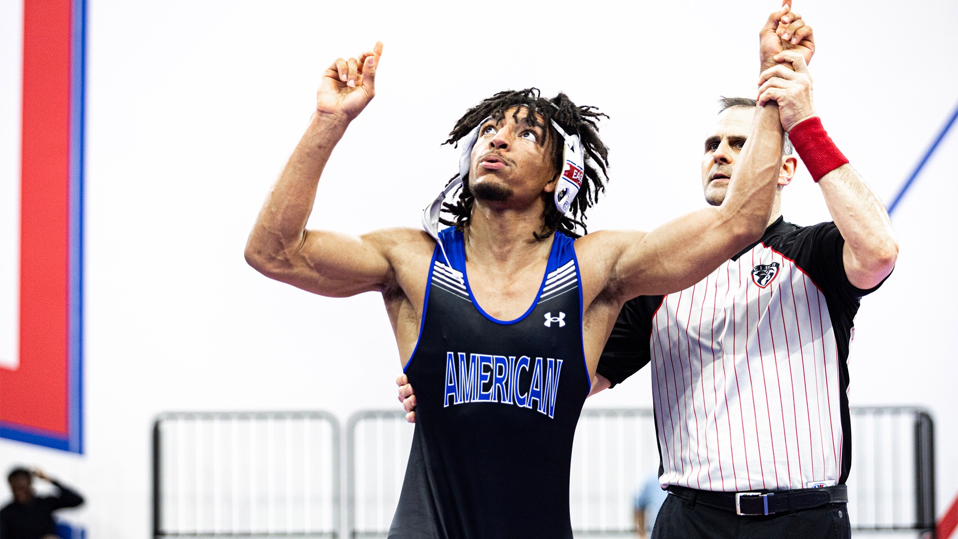 Caleb Campos getting his arm raised after winning a wrestling match.