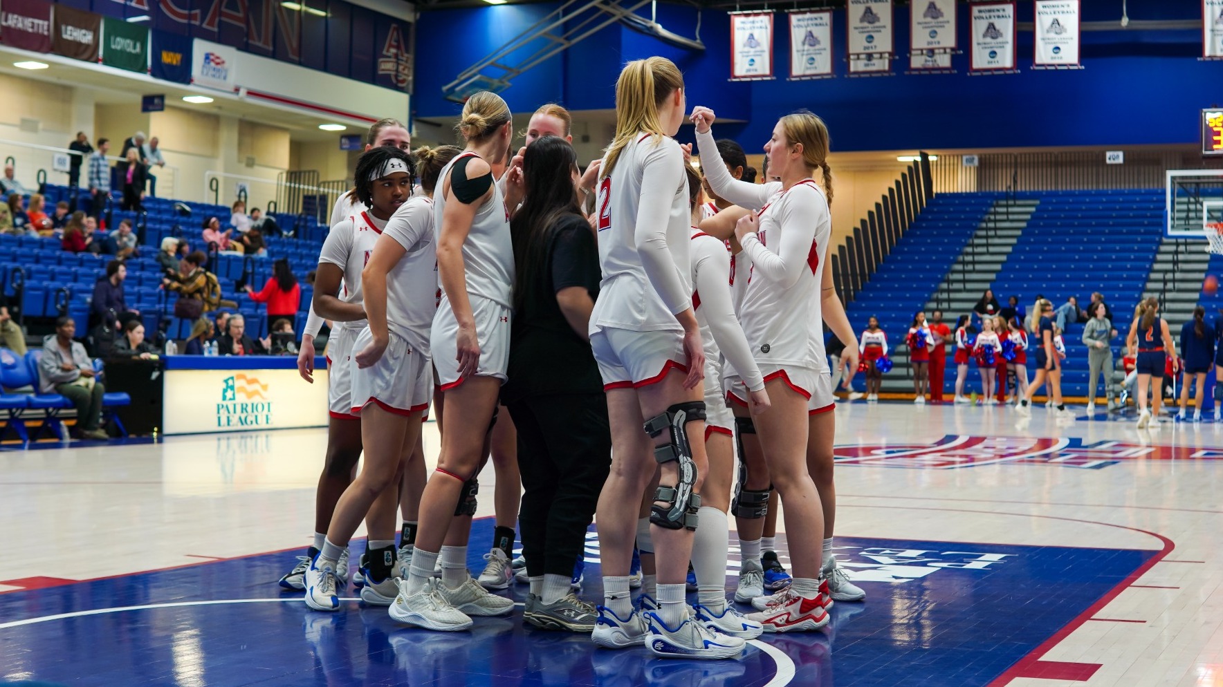 Women's Basketball huddles together on the court against Bucknell in Bender Arena.