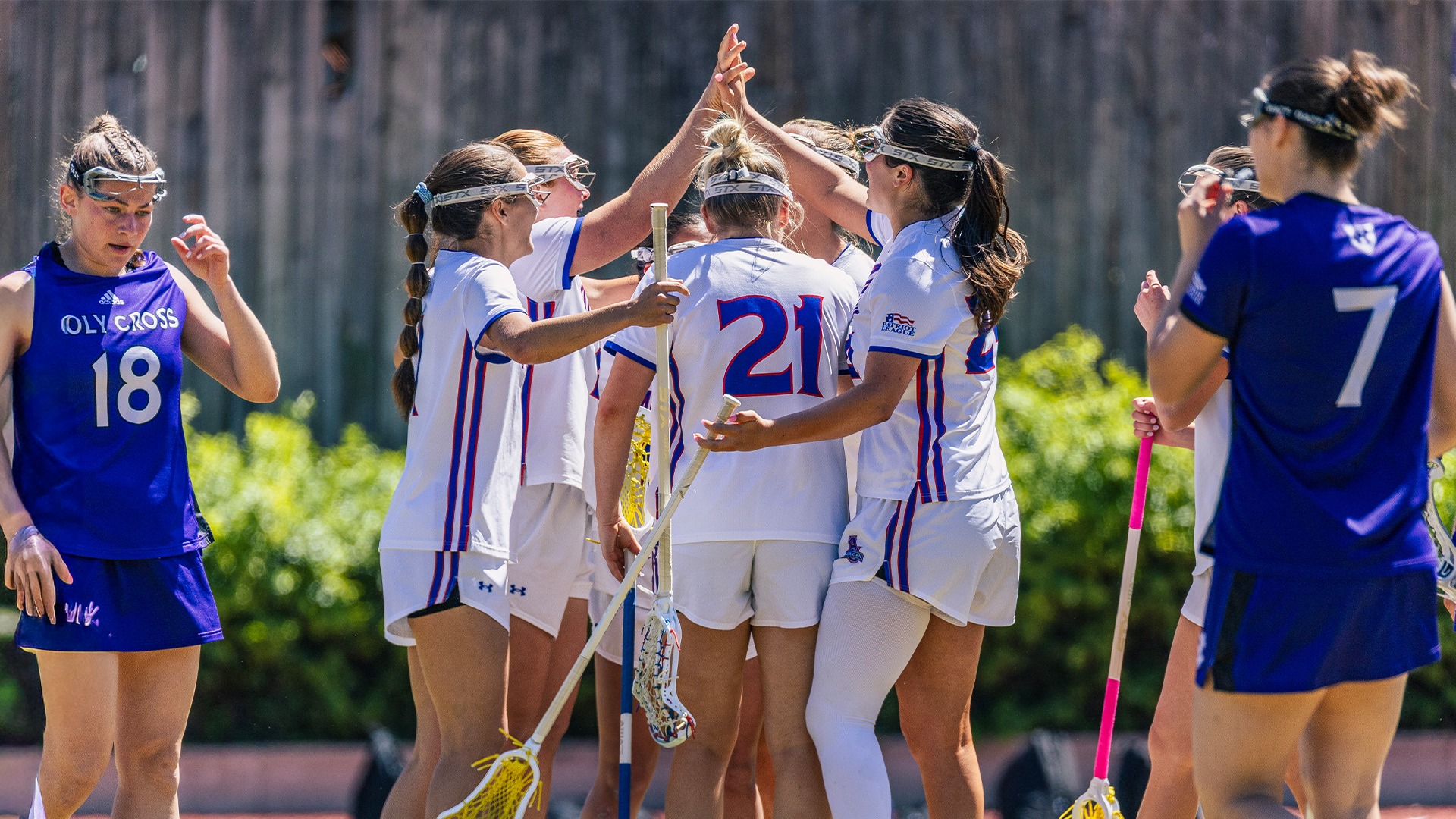 Reagan Murdoch and Annabelle Jackson high-fiving after a goal in a lacrosse game against Holy Cross. 