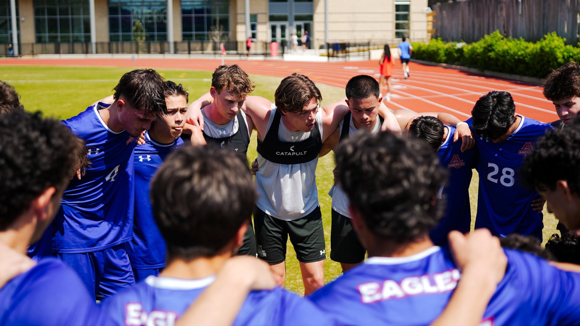 The men's soccer team in a huddle before a spring scrimmage.