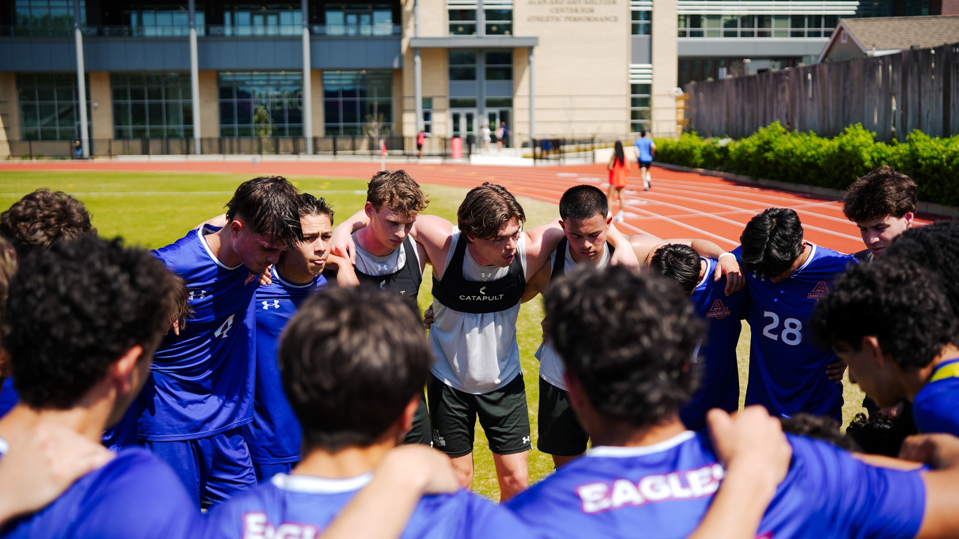 Men's soccer in a huddle before a spring game. 