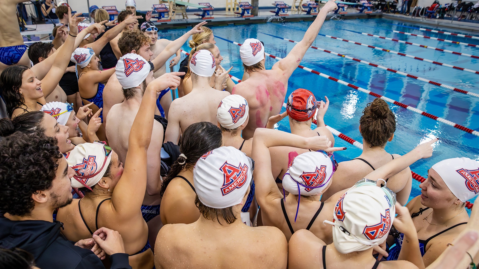 swim and dive team pointing and cheering at a meet