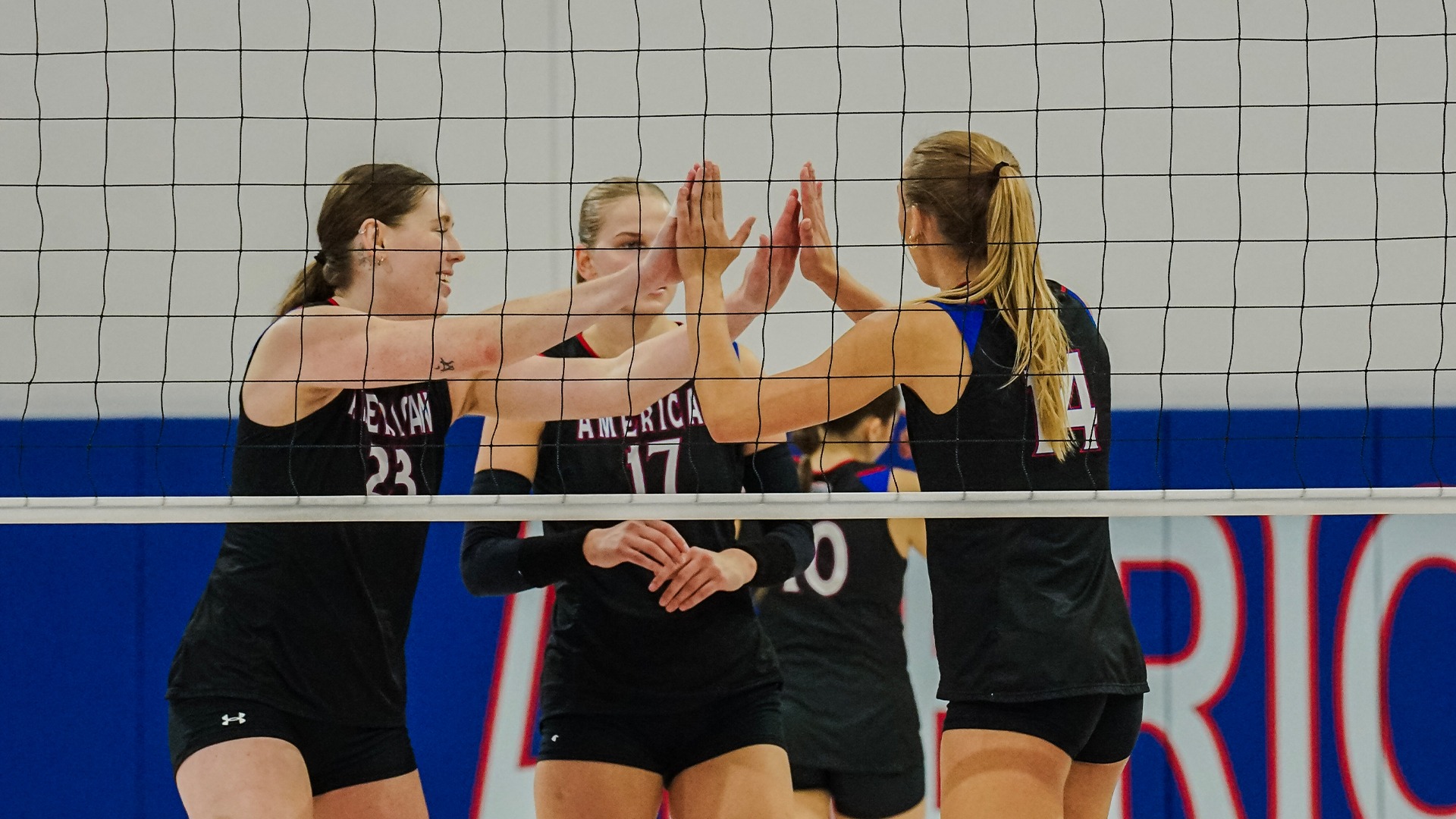 Carly Sciborski and Elise Sterling high-fiving after a point in a volleyball match against Howard. 
