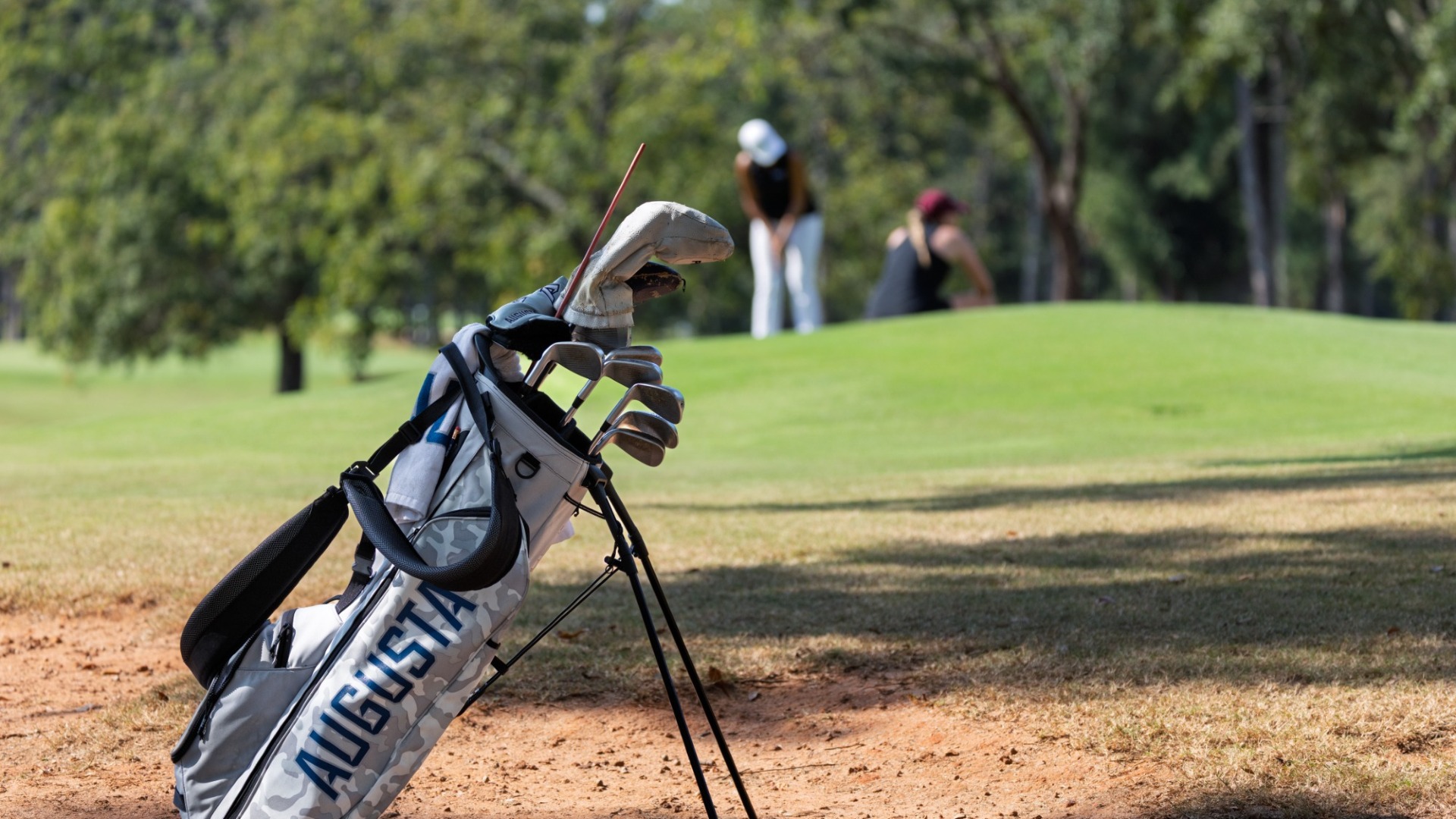 An Augusta golf bag sits on the course with a player in the background