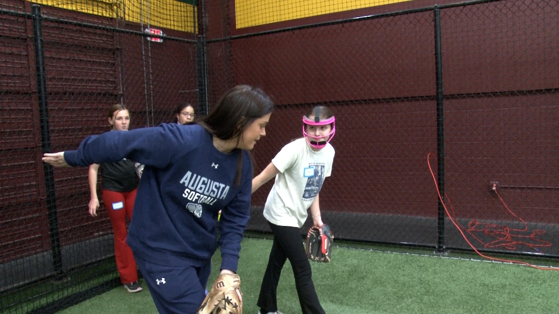 Augusta softball player gives pitching instruction to a younger player