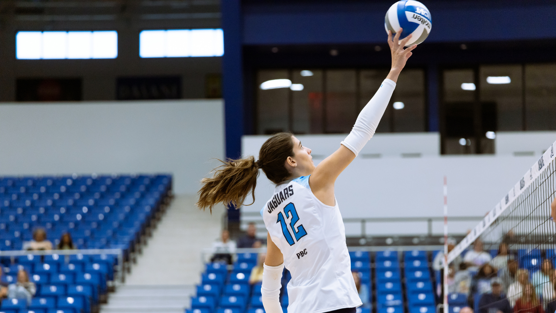 Angela Mateos attacking a volleyball at Christenberry Fieldhouse