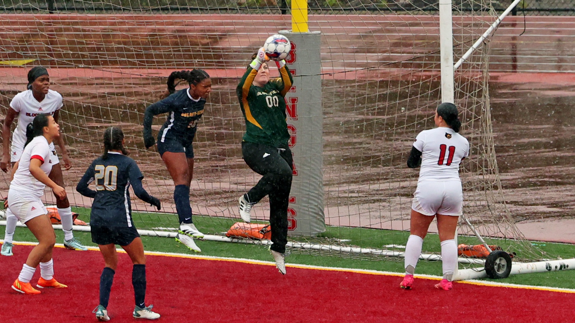 WOMEN'S SOCCER GOLDKEEPER MAKES A SAVE AMIDST A GROUP OF GOLDEY-BEACOM COLLEGE DEFENDERS
