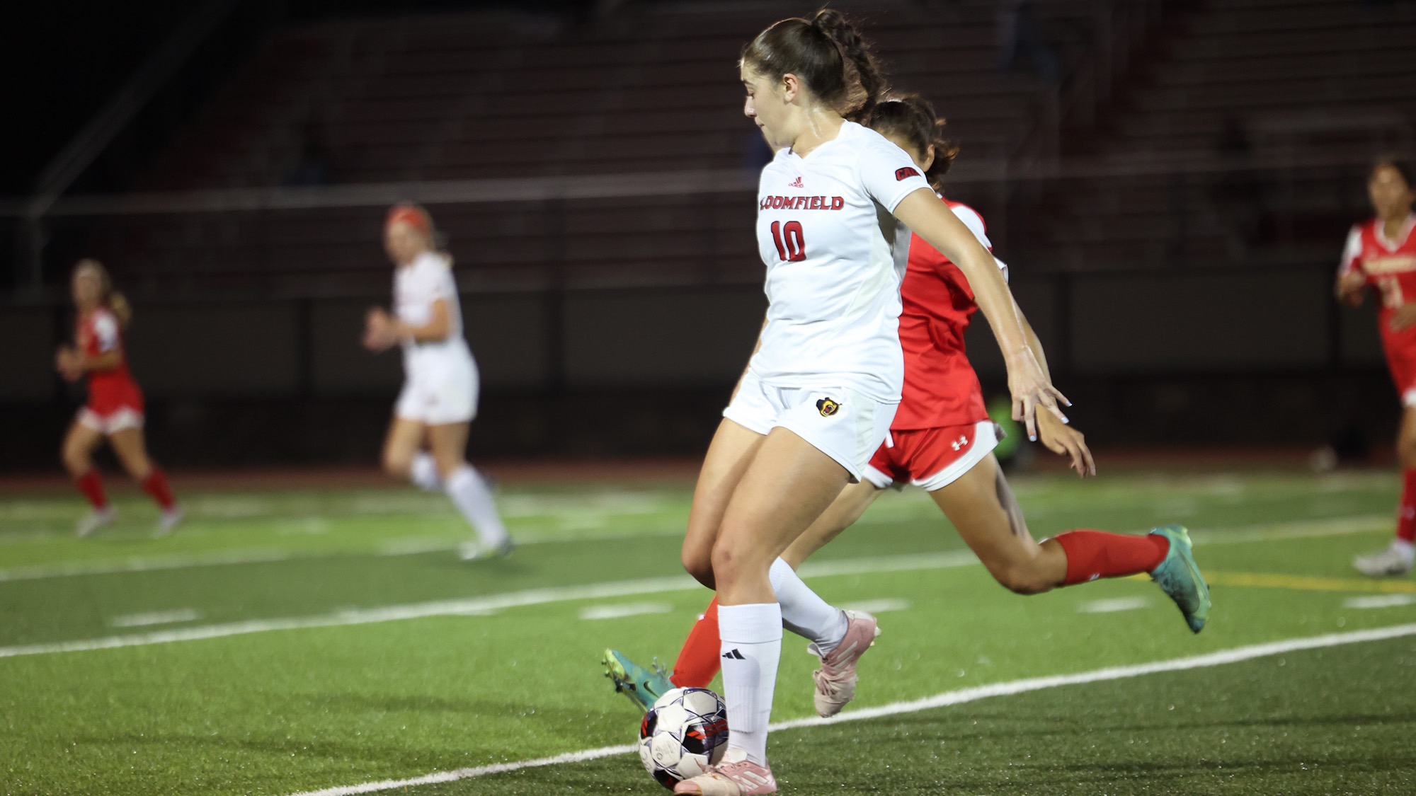 Women's soccer player going for the ball against a defender