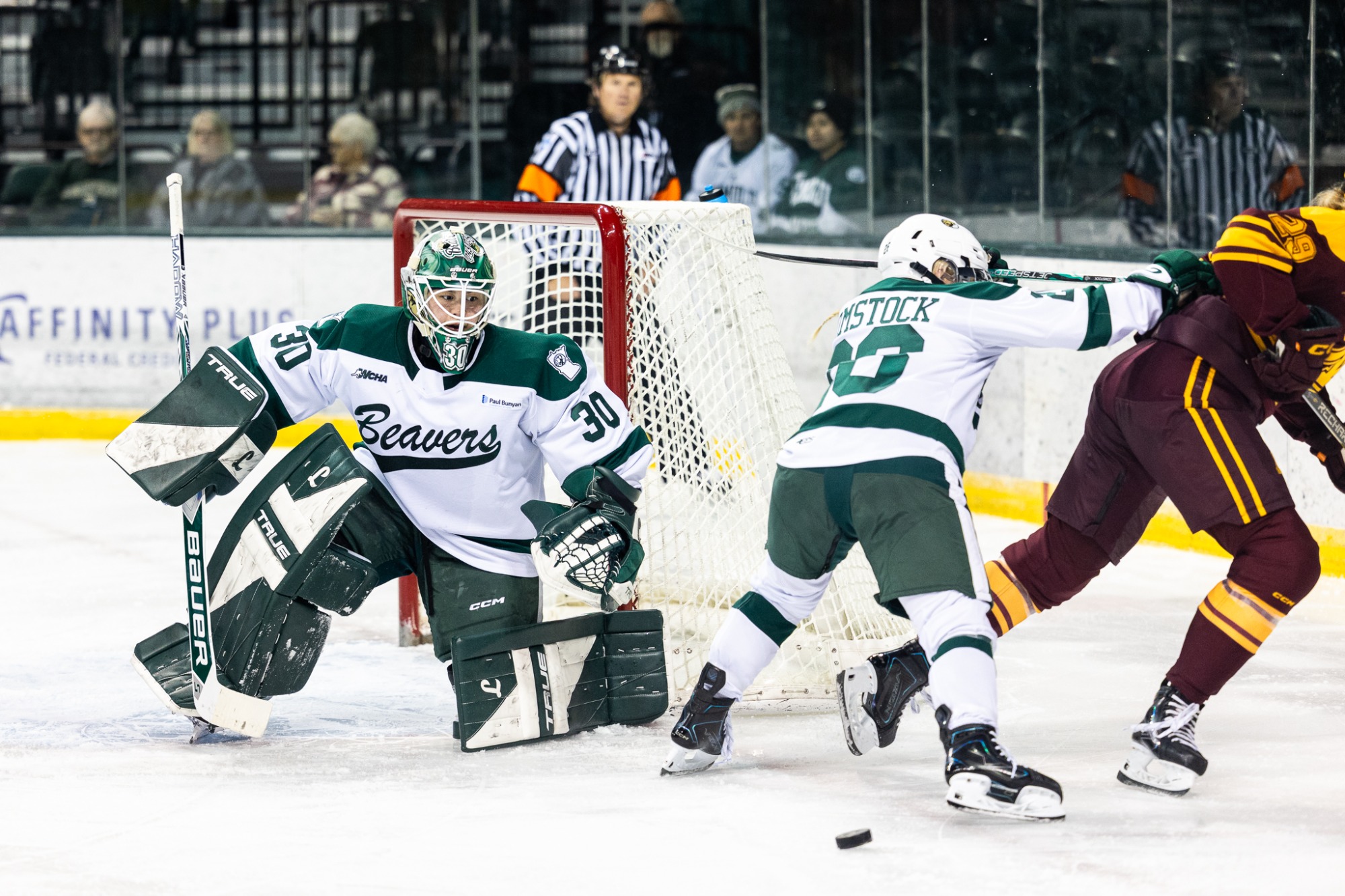 Sophia Villanueva watches the play while defender No. 13 battles a Minnesota skater behind the net.