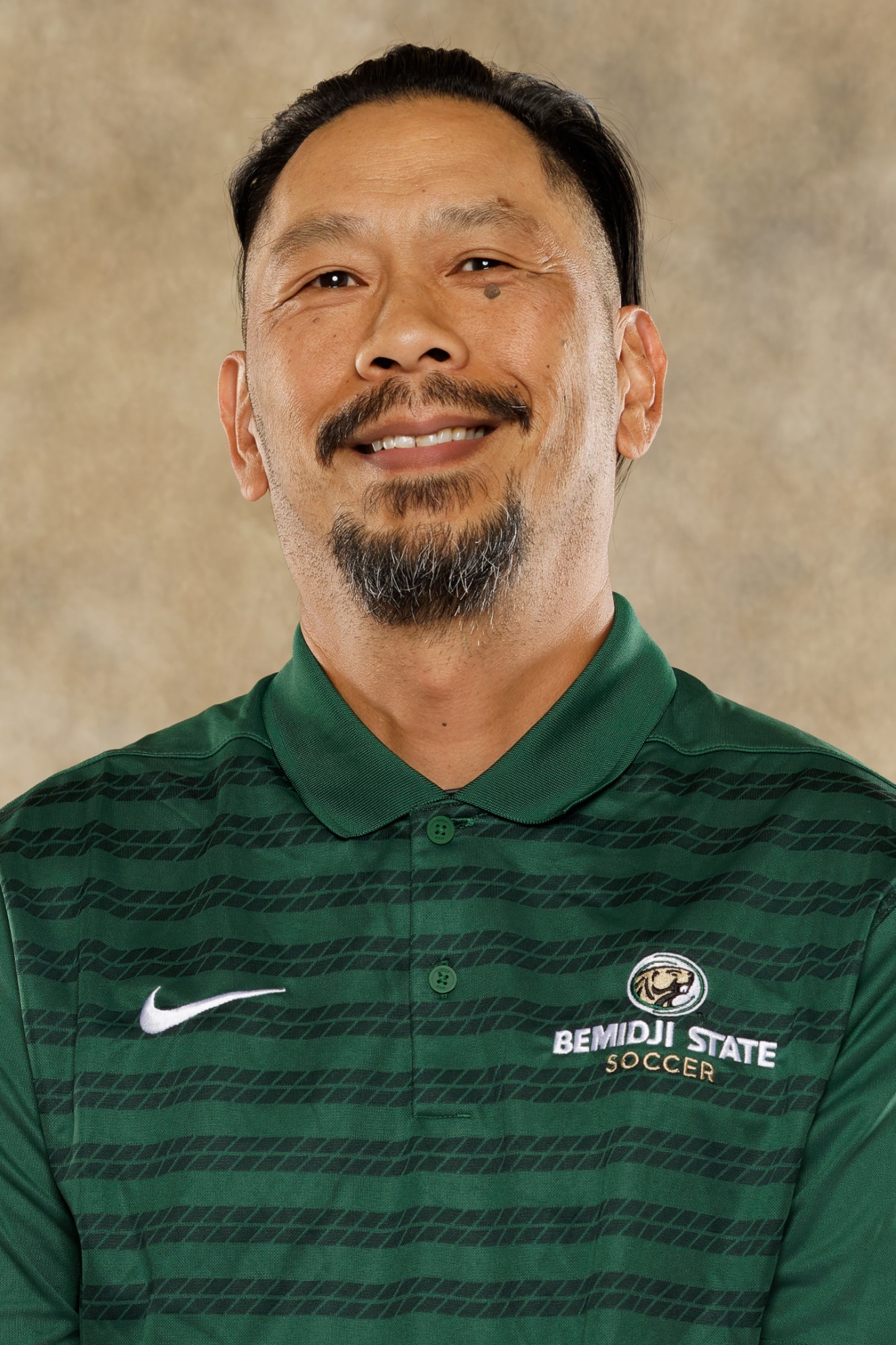 Portrait of Bemidji State soccer coach in green Bemidji State Soccer polo shirt with goatee