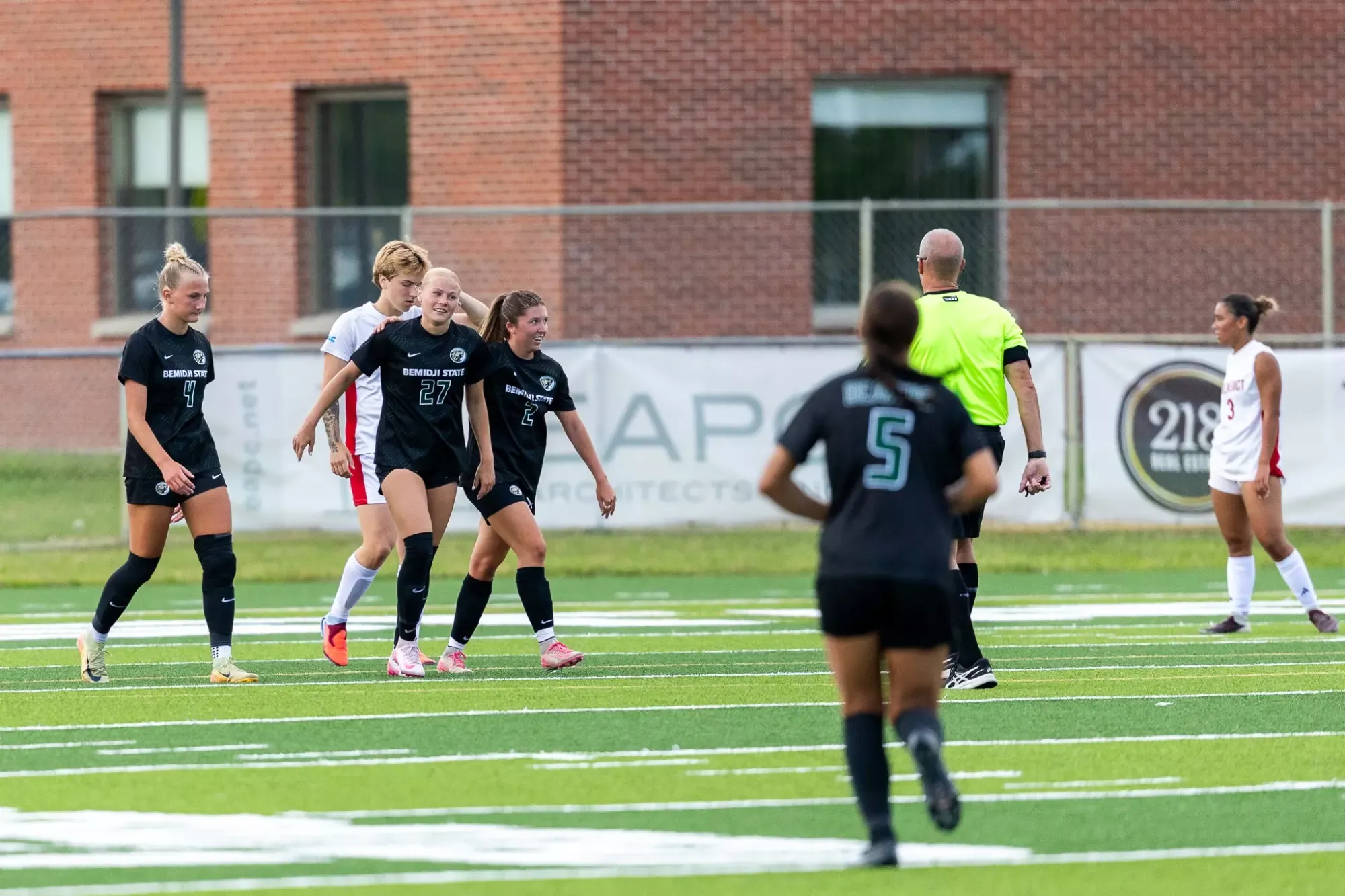 Bemidji State players walk upfield beside a referee after a scoring play.