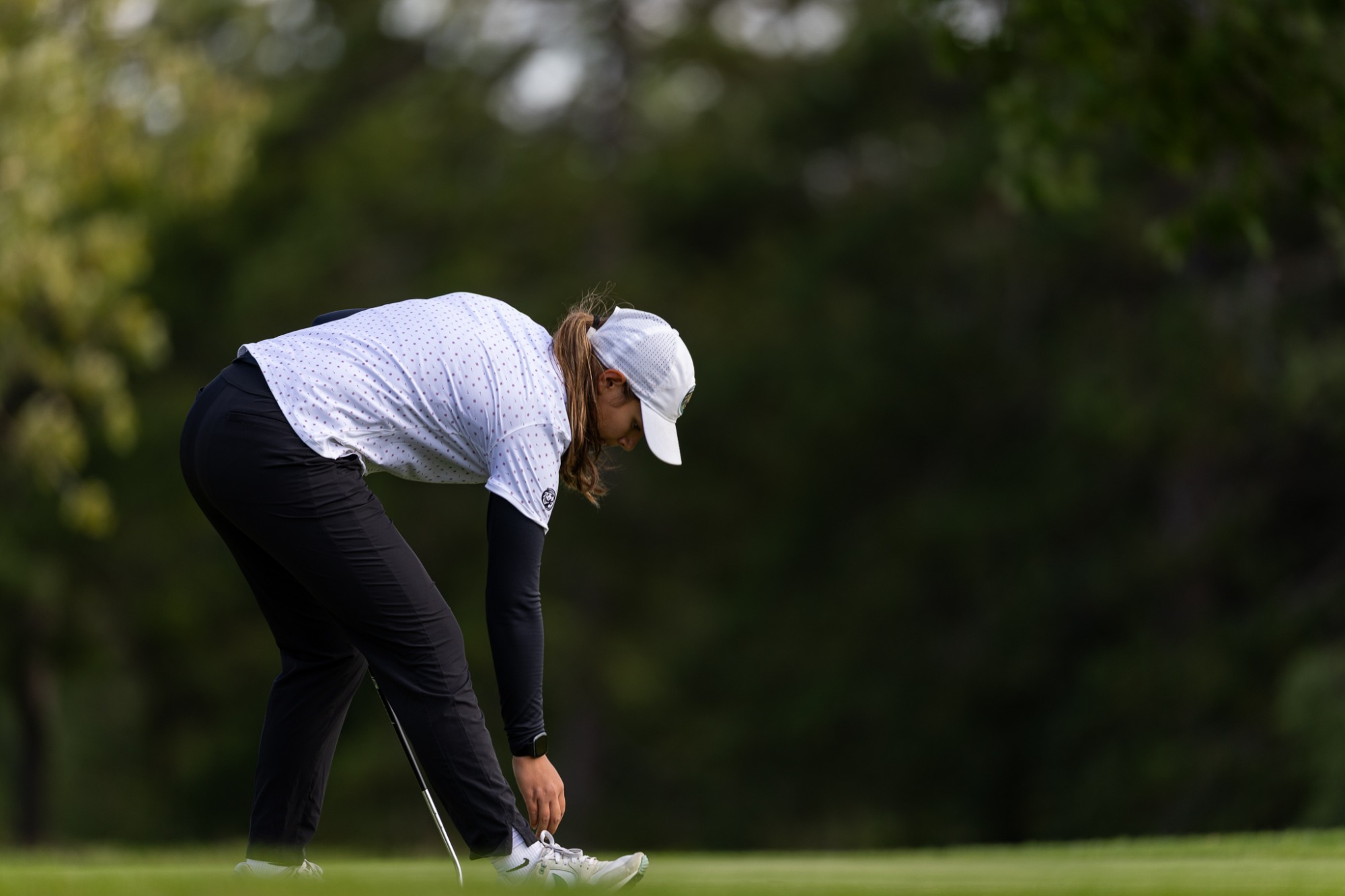 Sara Sroga bends down to mark a ball on the green.