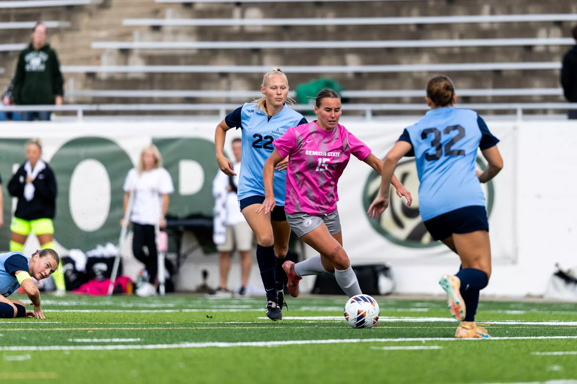 Bemidji State player No. 15 Madisen Fritel advances between Augustana players No. 22 and No. 32.