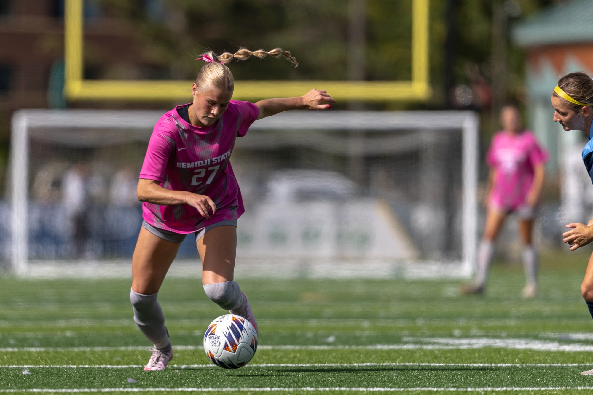 Molly Burkstrand (27) dribbles toward an Augustana defender.