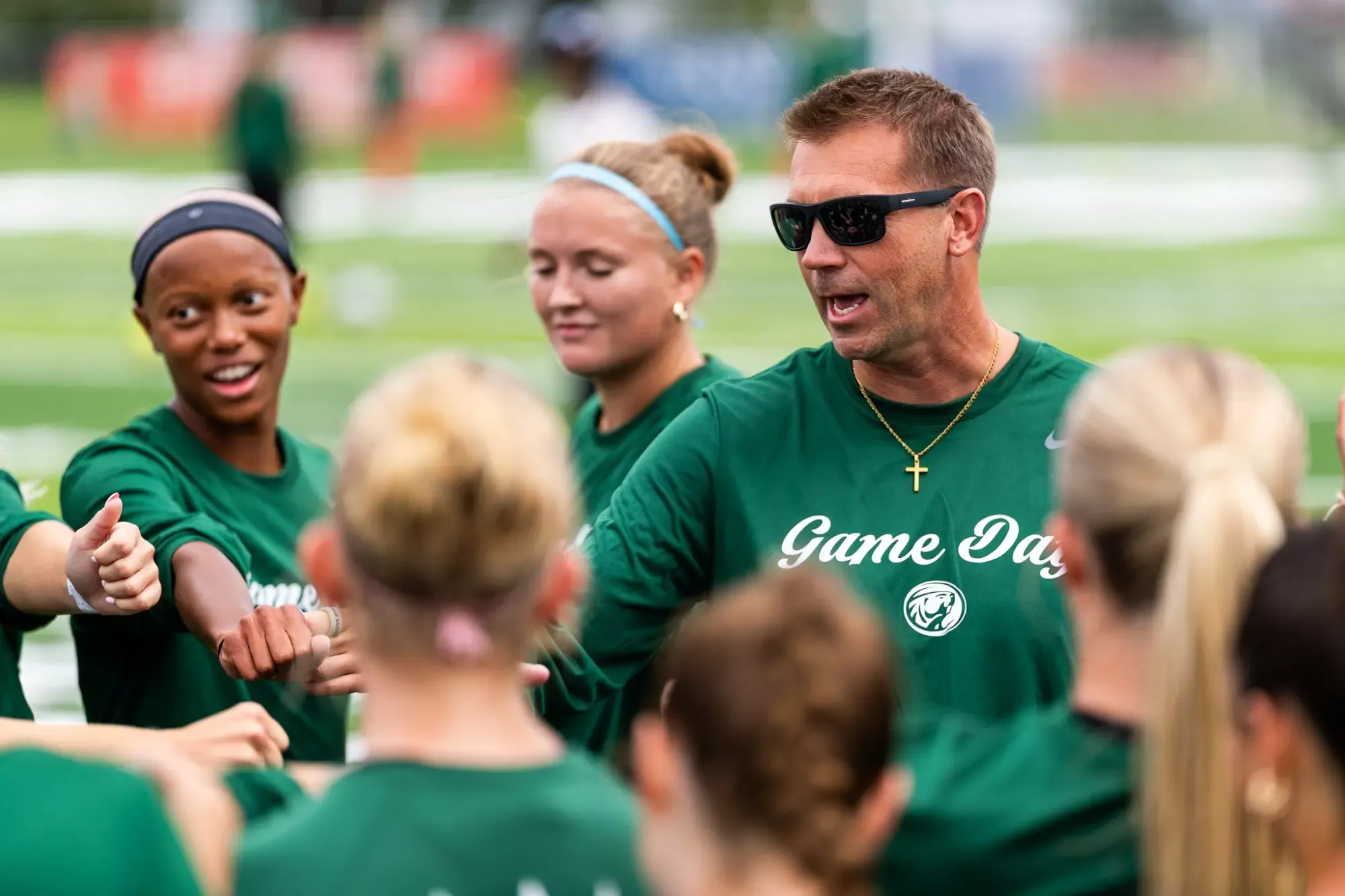 Jim Stone coach addresses players gathered in a pregame team huddle on the field.