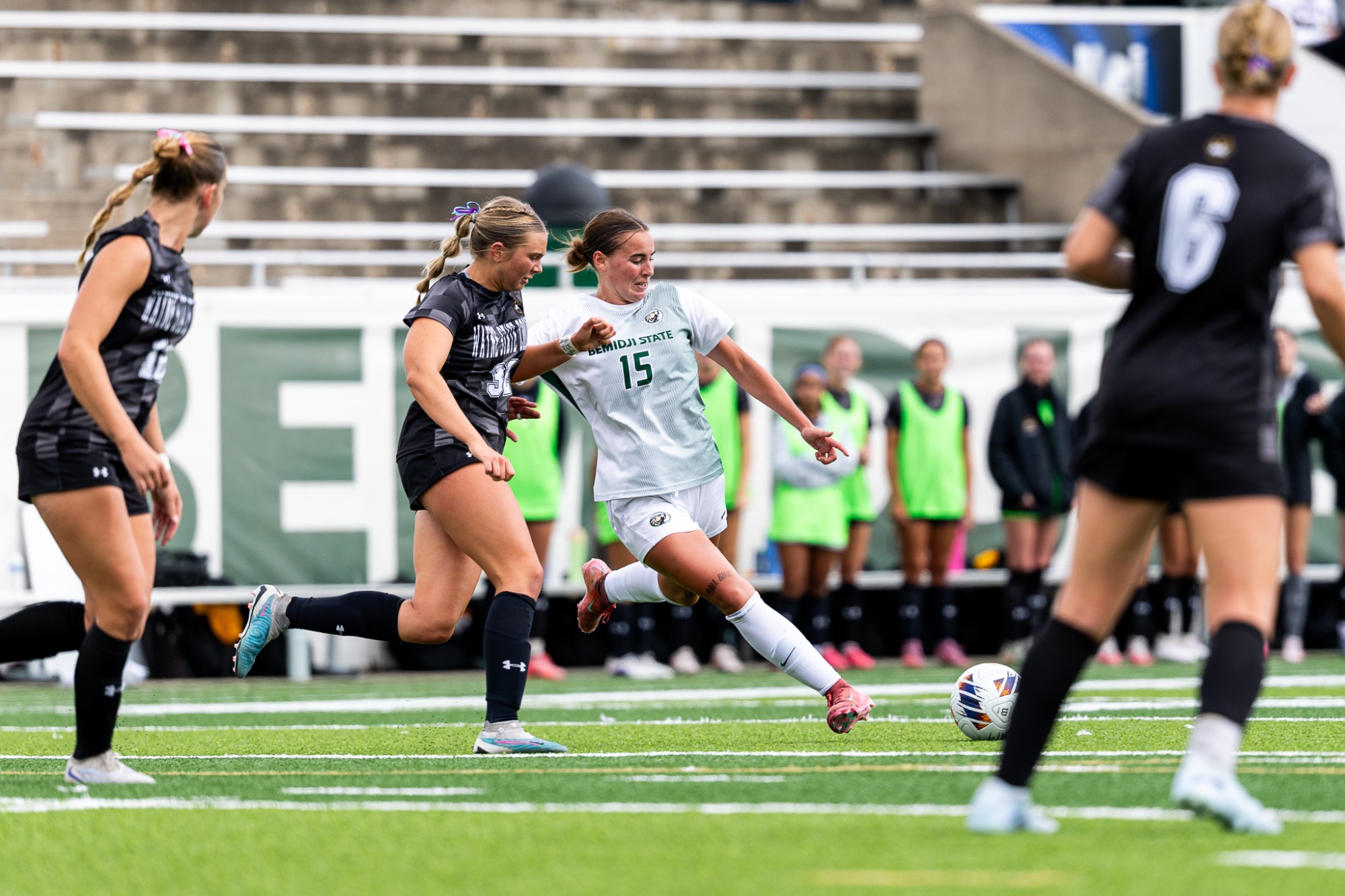 Madisen Fritel swings a leg through the ball while a Wayne State defender closes in to defend.