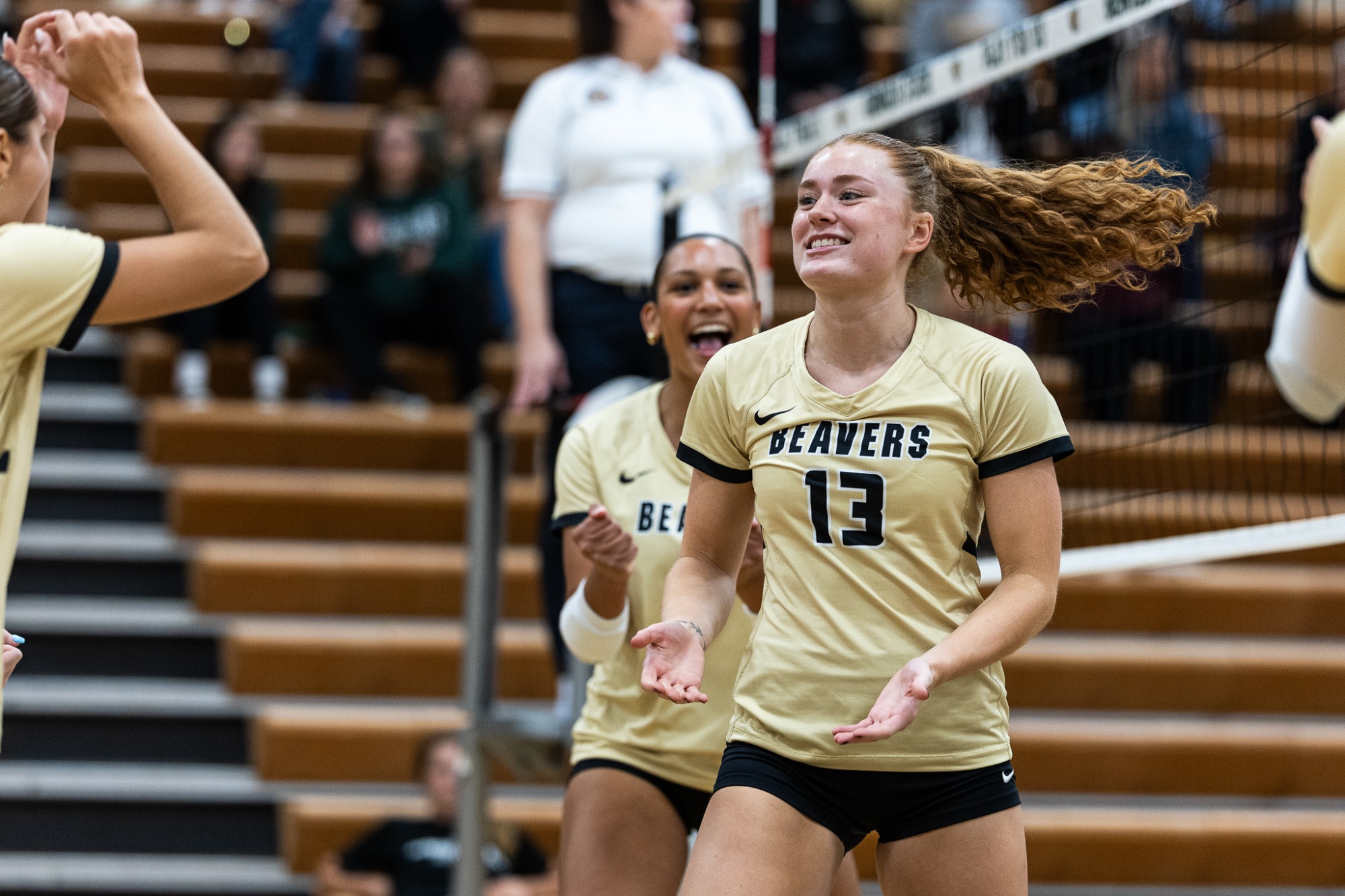 Ava Athman reacts near the net as teammates celebrate a point against Northern State.