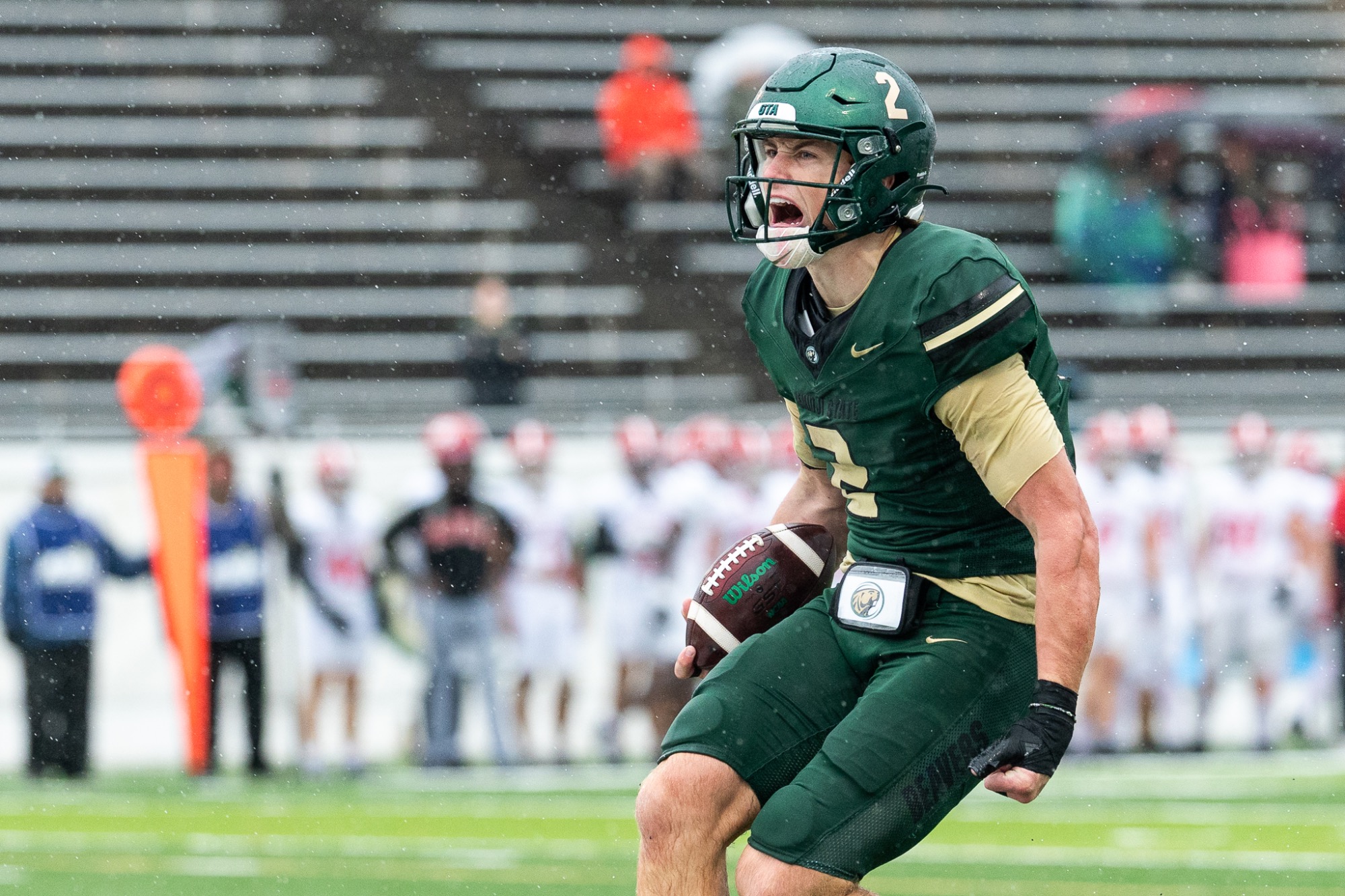 Connor Carver carries the football and celebrates a long run during a rainy game against Minot State University.