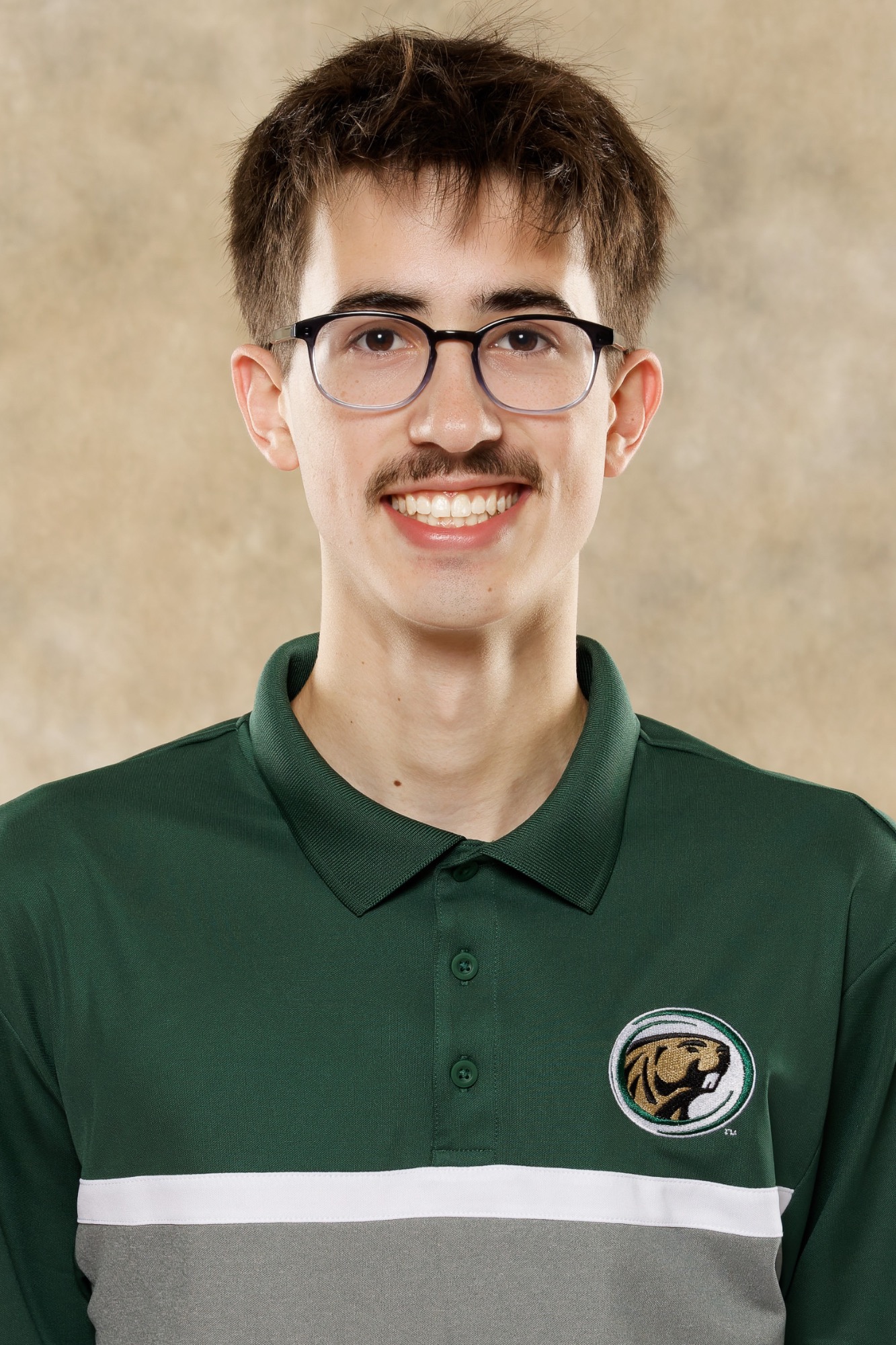 Head-and-shoulders portrait of a Bemidji State men's basketball student manager wearing a green Bemidji State polo shirt, facing the camera against a neutral studio background.