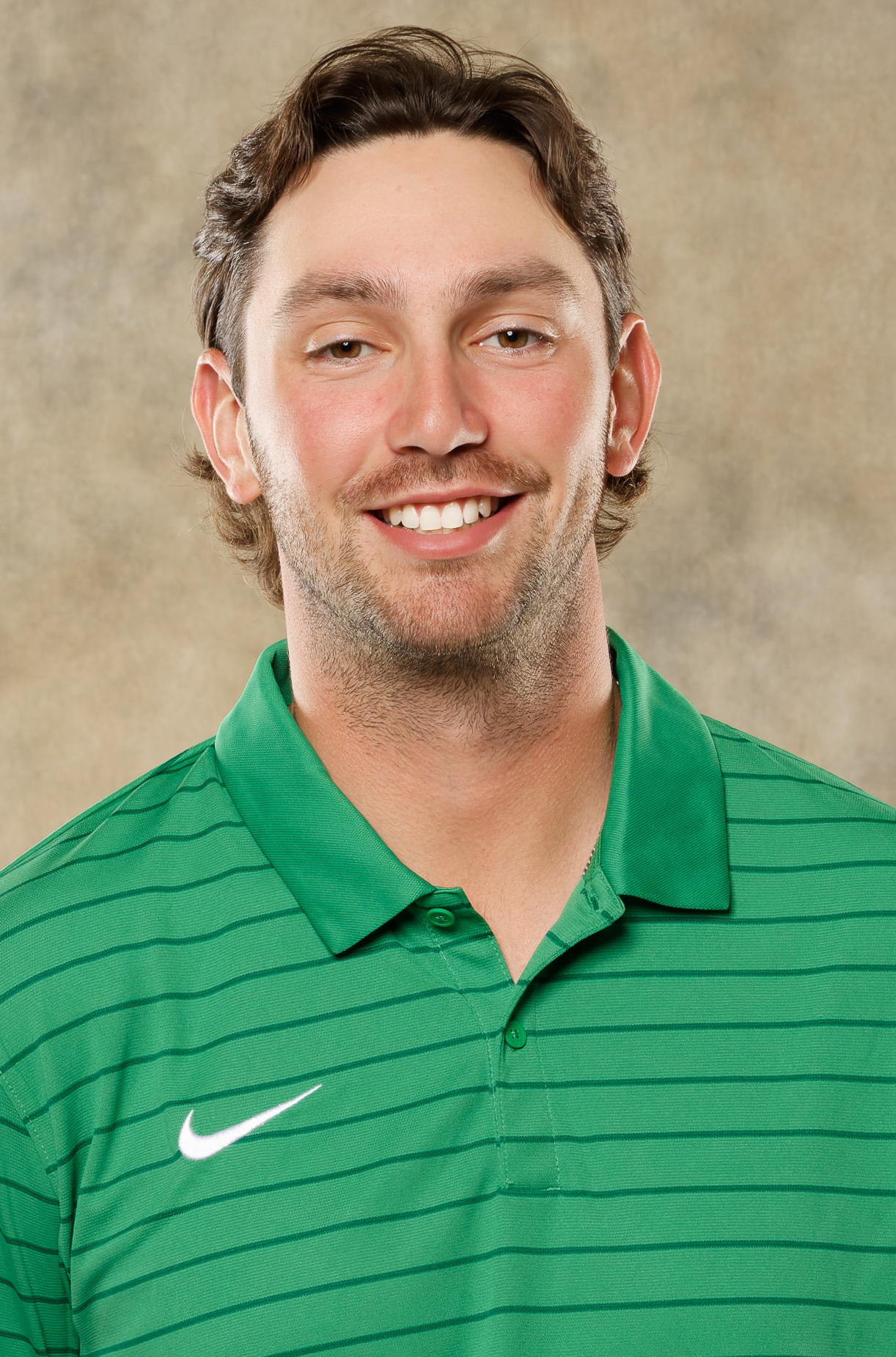 Headshot of Ben Corbid with short curly dark hair wearing a green striped polo shirt, facing the camera against a neutral beige backdrop.