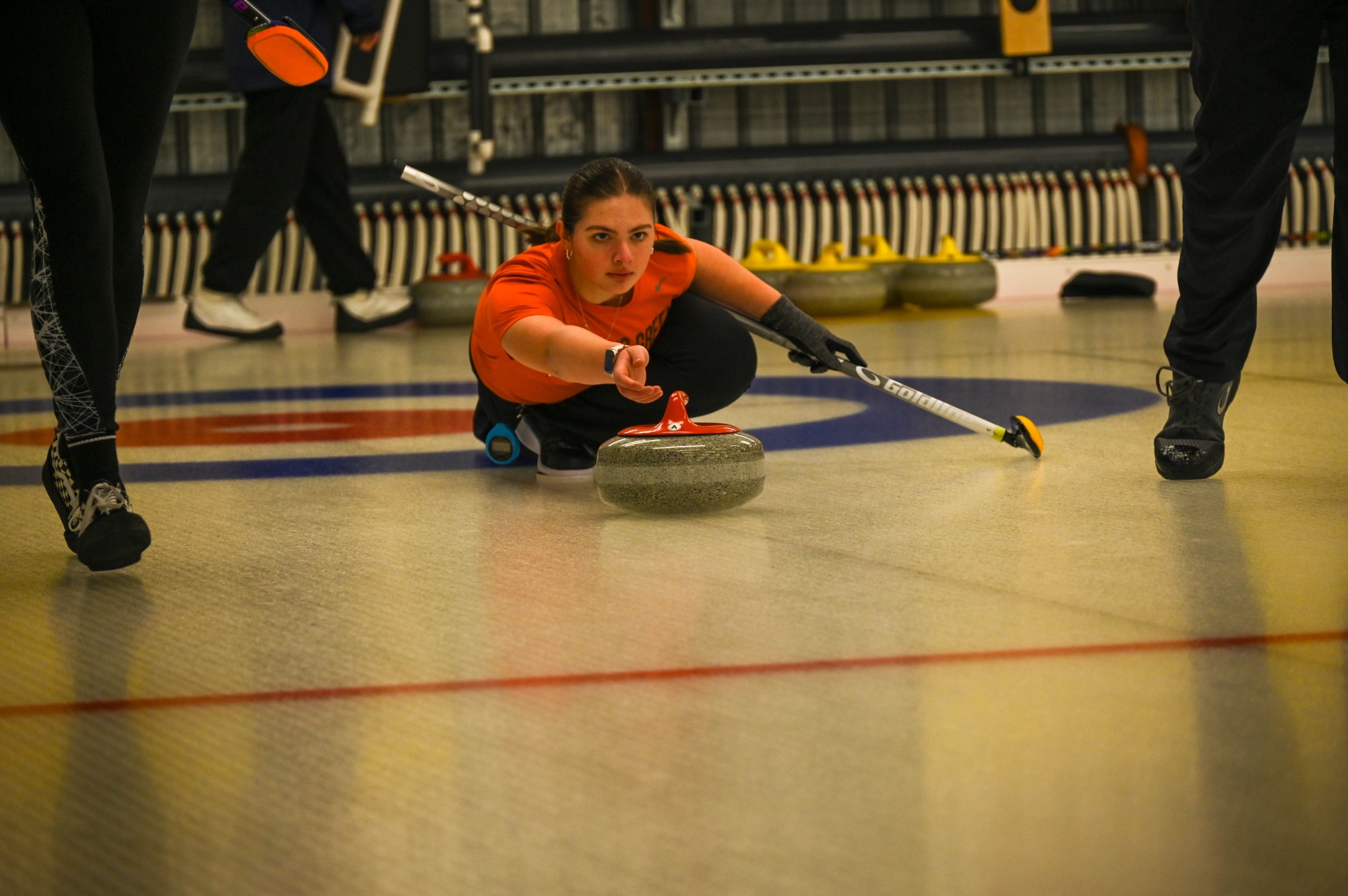 Member of the Club Curling team lunges forward and slides her stone down the ice.