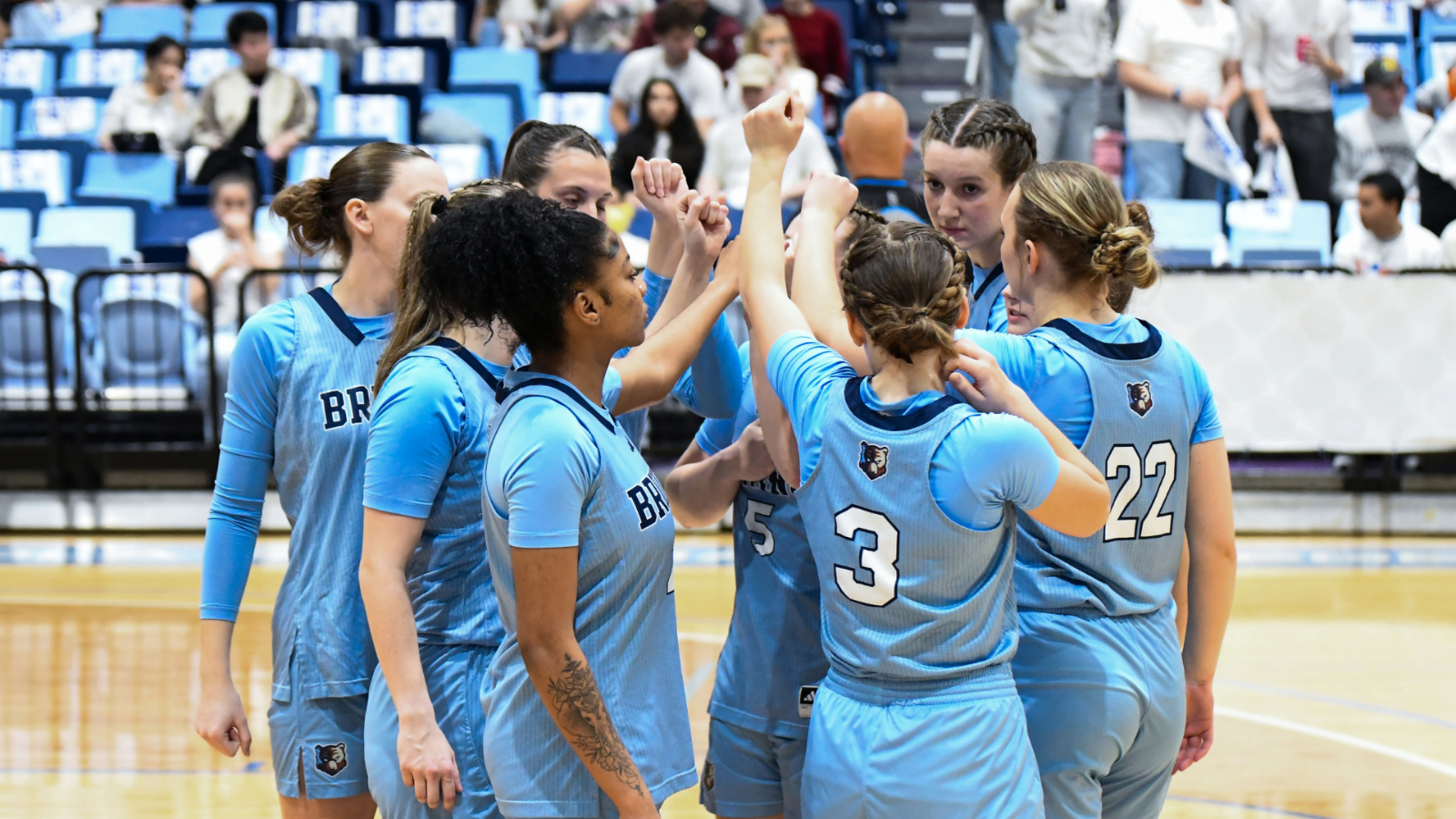 Bruins basketball players huddled together with their hands in the circle