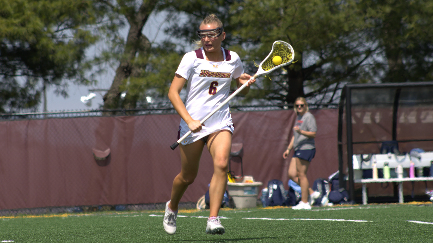 Delaney Fox stands on the field with the ball in her stick. 