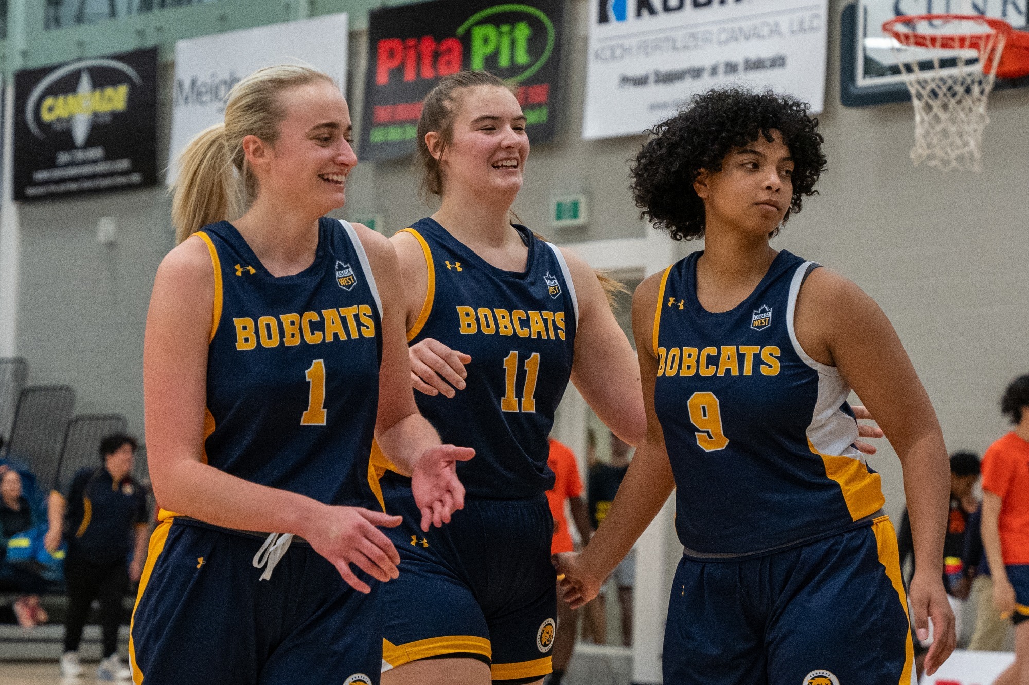 Women's basketball team members Cali Yates, Eden Tabin and Mahe Rabesa share a moment to smile during the 2023-24 season