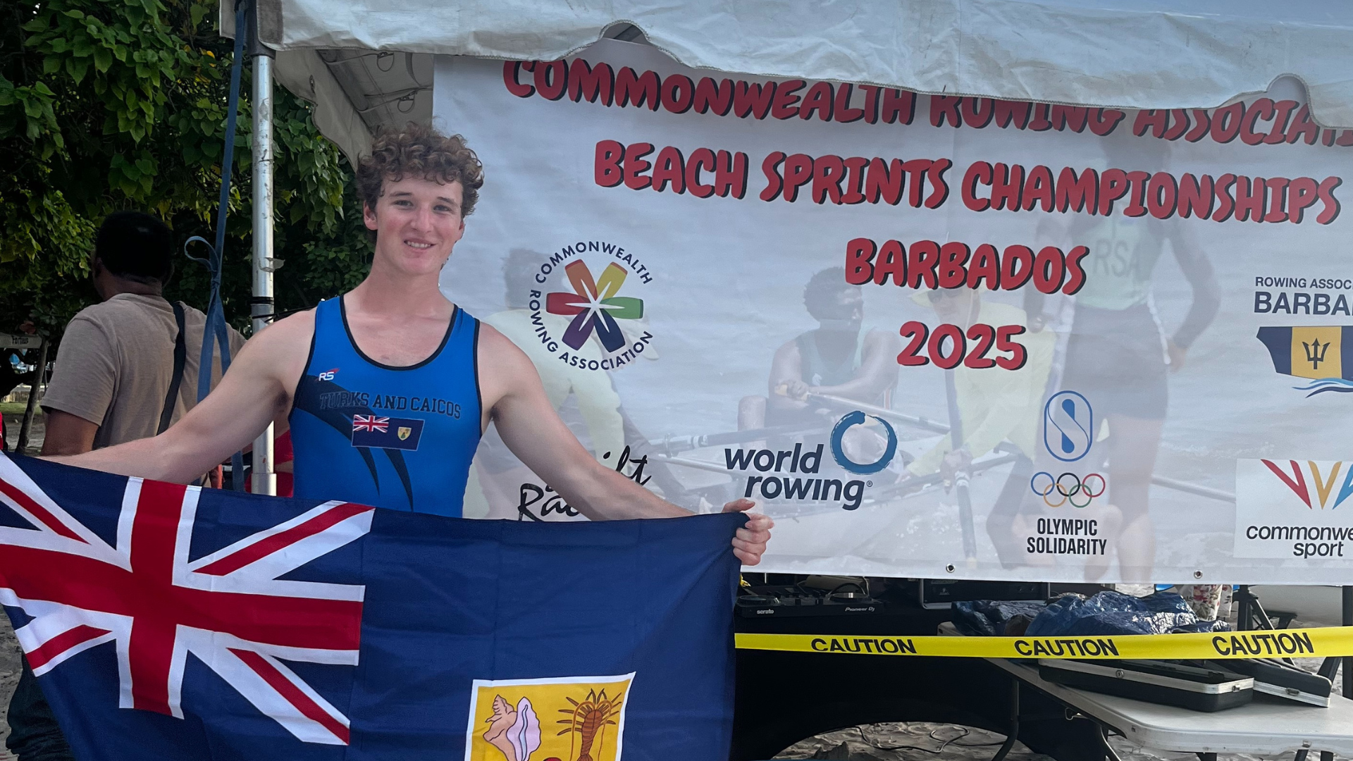 Shawn Nesbitt pictured with the Turks and Caicos flag at the 2025 Commonwealth Rowing Association Beach Sprint Championships